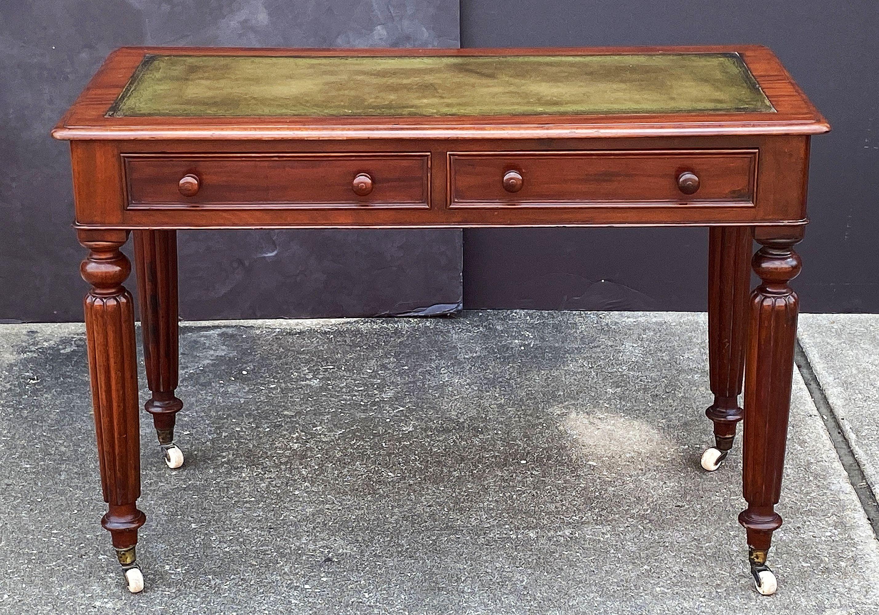 Un raffinato tavolo o scrivania inglese in mogano della fine del XIX secolo, in stile William IV, con un piano in pelle verde goffrata su un fregio di due cassetti - ogni cassetto è dotato di tiretti con pomello - e poggiante su gambe a reticolo con