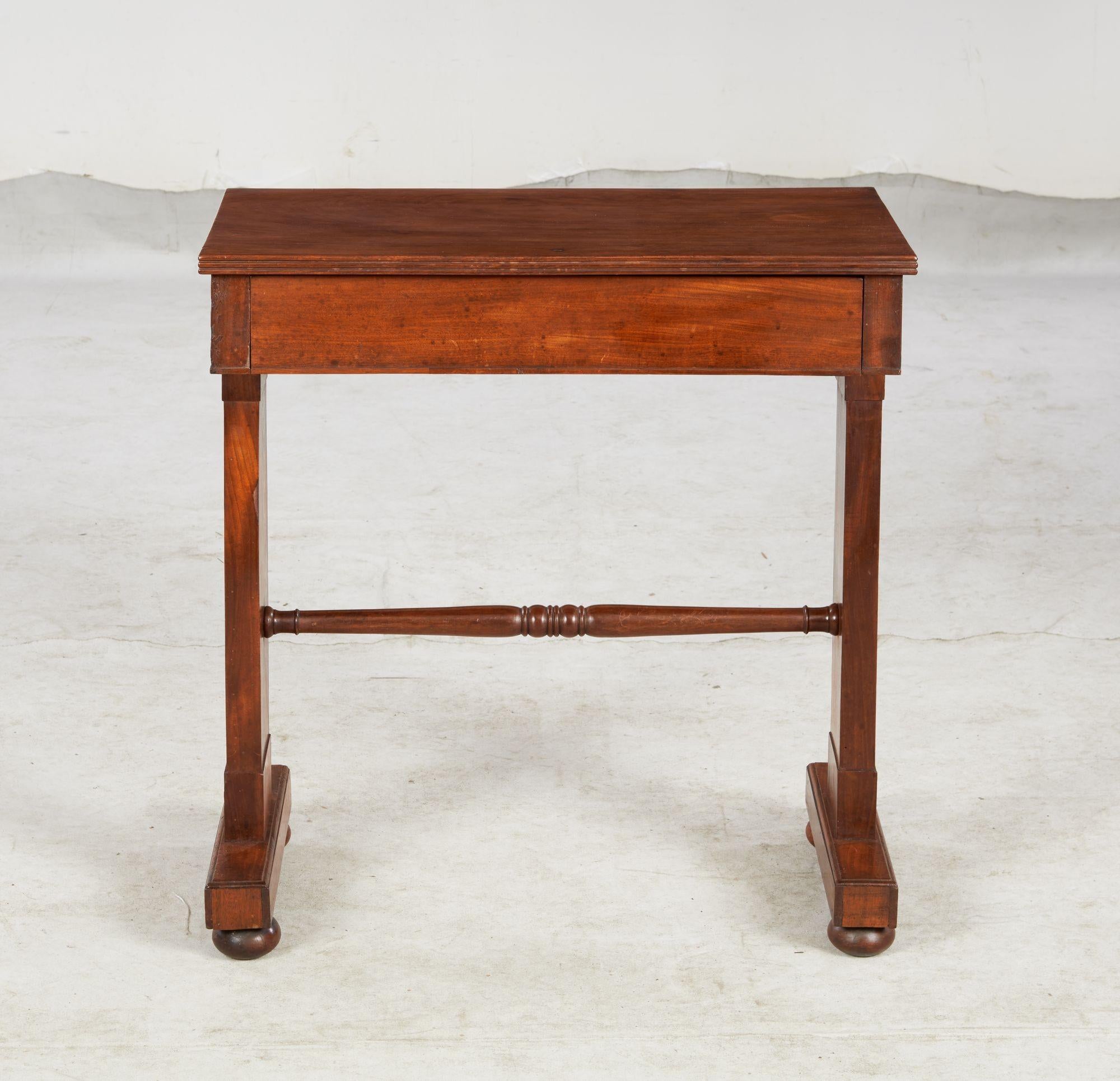 Table d'écriture ou d'appoint William IV de forme architecturale très nette, le plateau en acajou à une planche bien figuré surmontant un tiroir et soutenu par des tréteaux reliés par un châssis tourné, l'ensemble étant réalisé dans un bois riche et