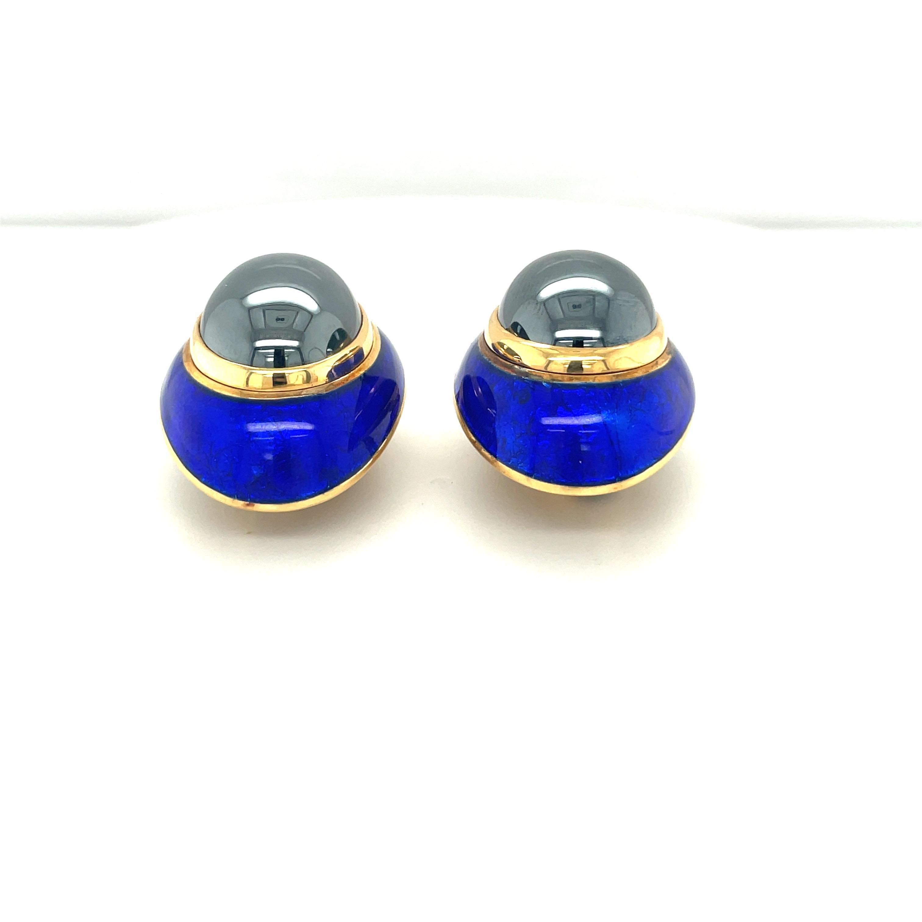 These 18 karat yellow gold earrings features beautiful hematite oval cabochon, bezel set surrounded by cobalt blue guilloche enamel. 

This piece is signed and stamped with the makers mark, and with 18K