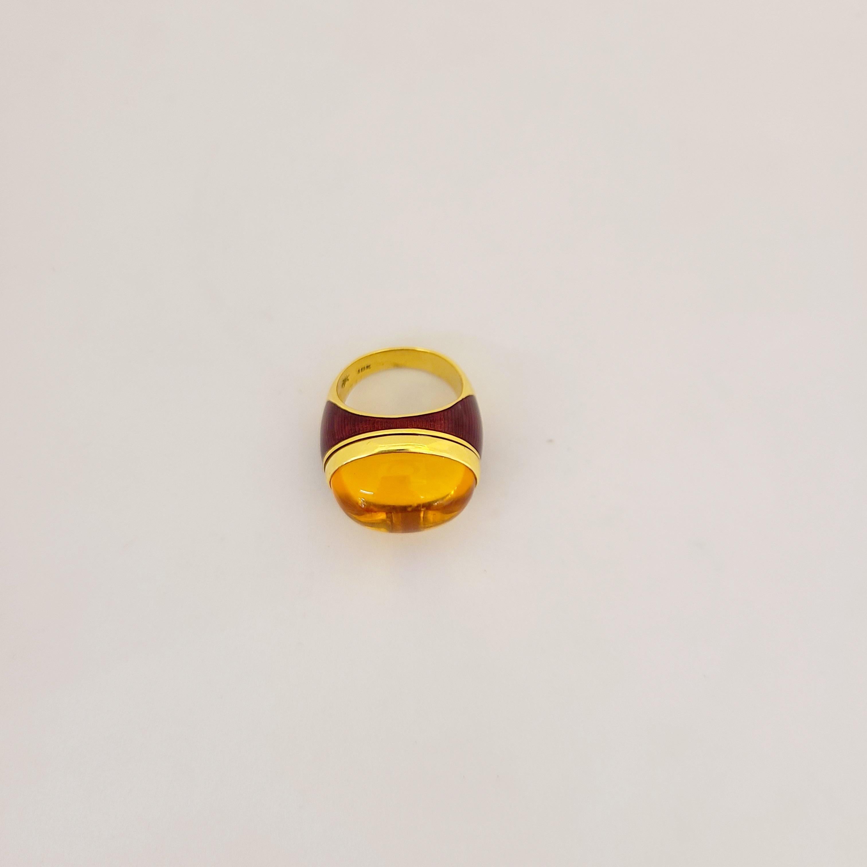 This 18 karat Yellow Gold rings features a beautiful citrine oval cabochon, bezel set surrounded by red guilloche enamel. 
Ring Size 6.75 
This piece is signed and stamped with the makers mark, and with 18K
