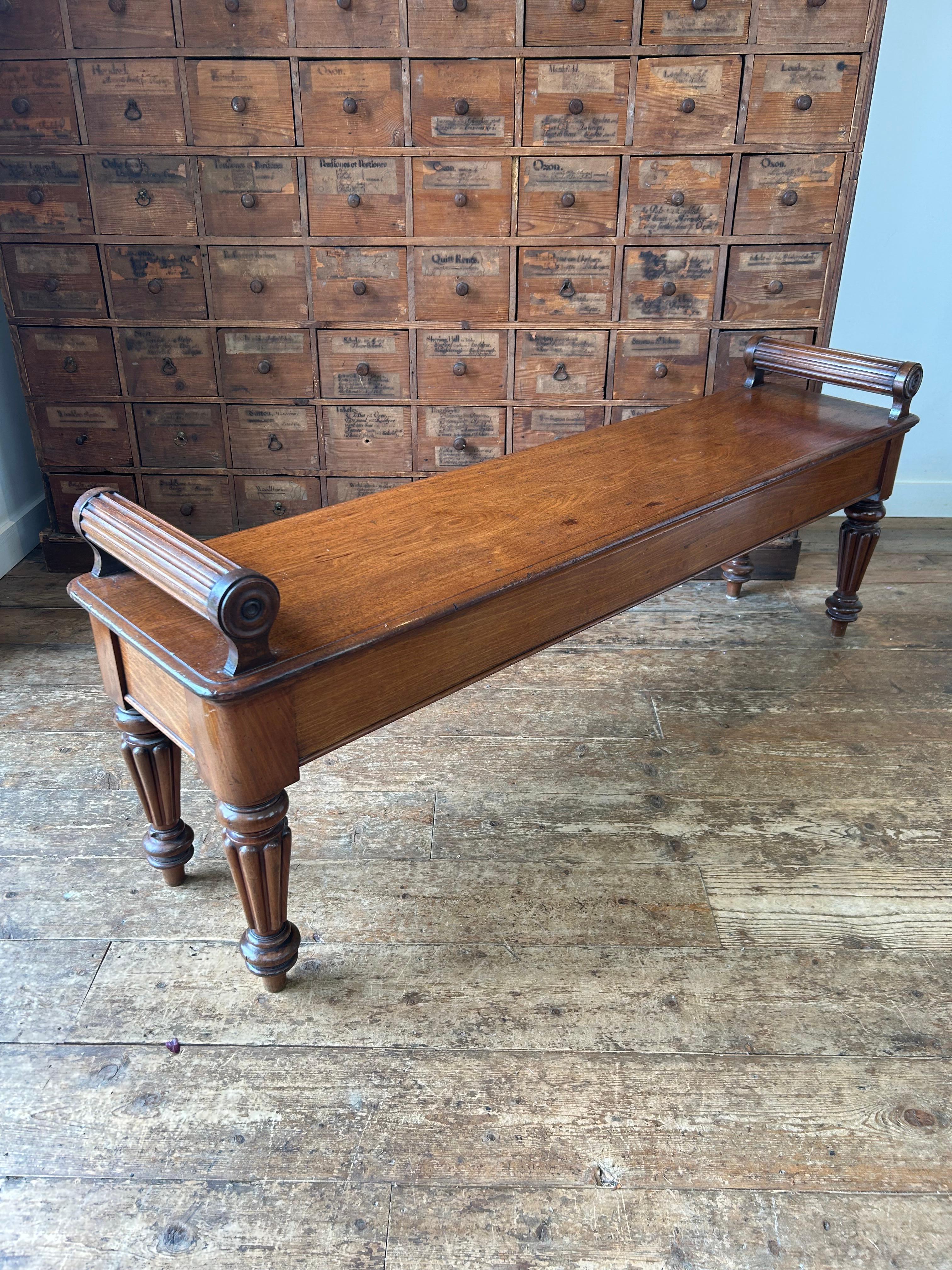 Grand banc d'entrée en acajou de style William XV, à la manière de Bolsters, avec un plateau d'une seule pièce à double moulure, flanqué de traverses à cannelures surélevées et de ronds tournés, reposant sur des pieds tournés et cannelés. Le dessous