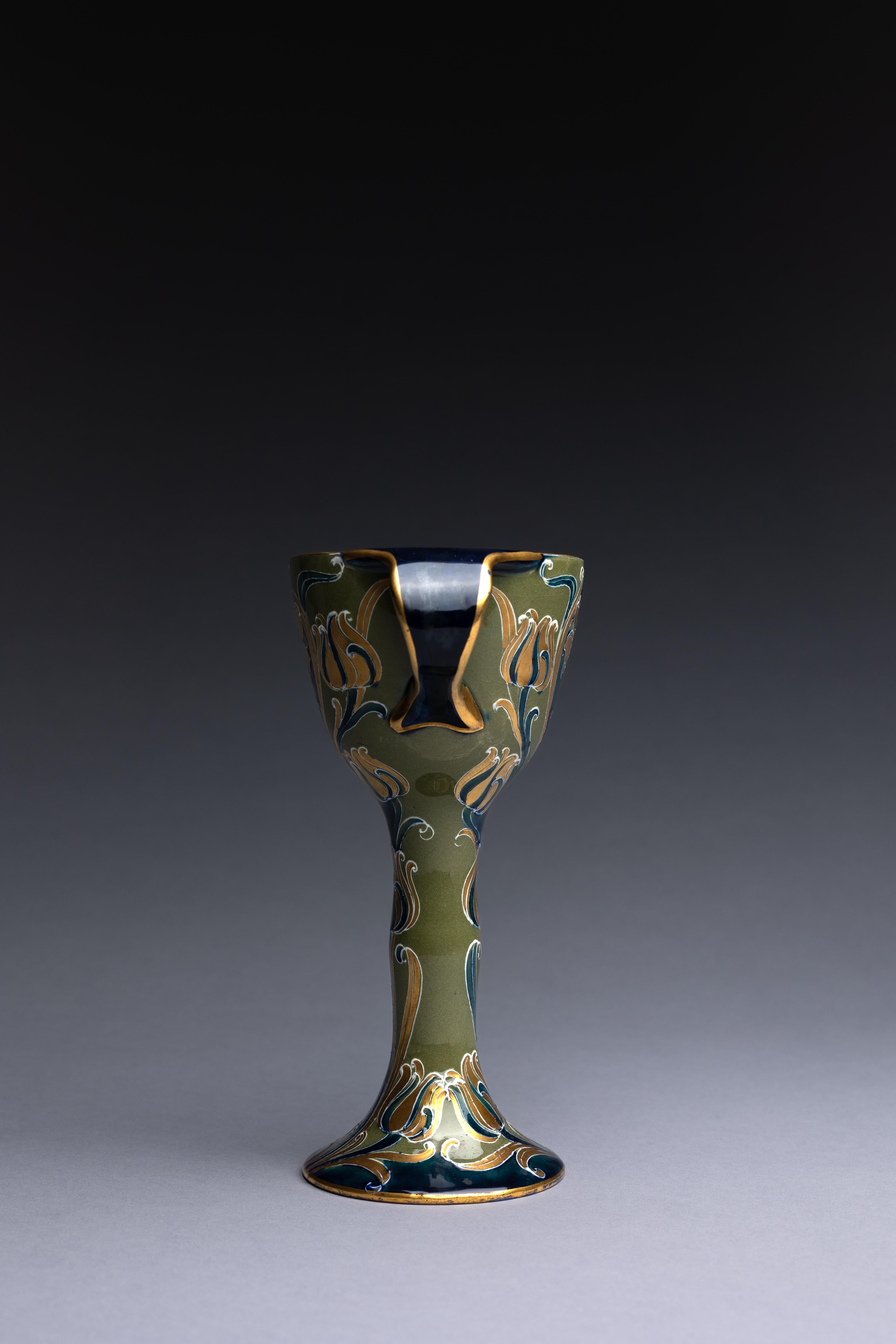 A decorative pottery goblet created by William Moorcroft for James MacIntyre & Co. in 1903.

This goblet is part of William Moorcroft's Green and Gold Florian line. In producing these wares, Moorcroft utilized a medieval ceramic technique of