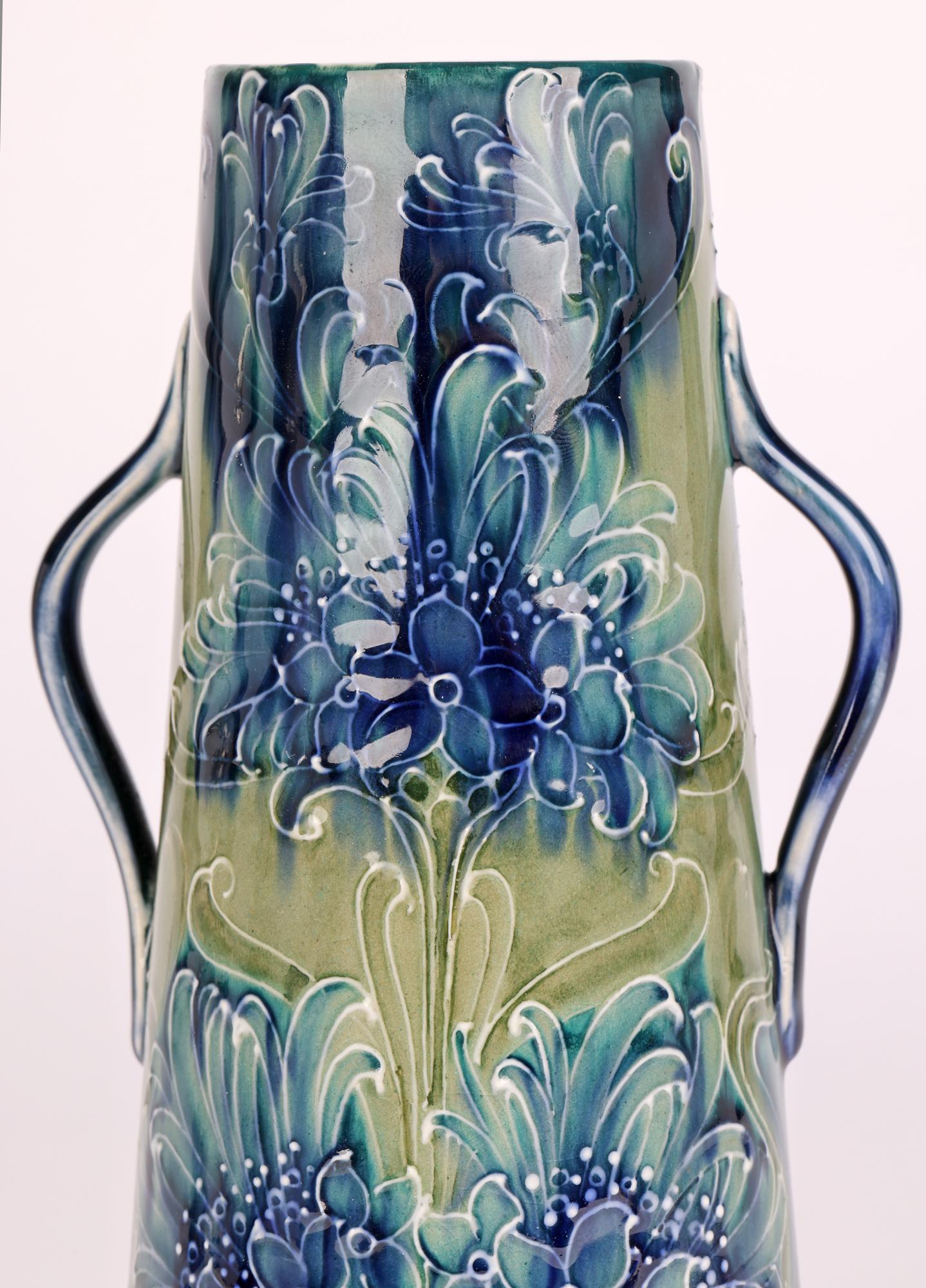A rare James MacIntyre & Sons art pottery twin handled vase decorated in the blue cornflower pattern by William Moorcroft (British, 1872-1945) and dated 1898. This wonderful early example has a tall slightly conical shaped round body with a wide