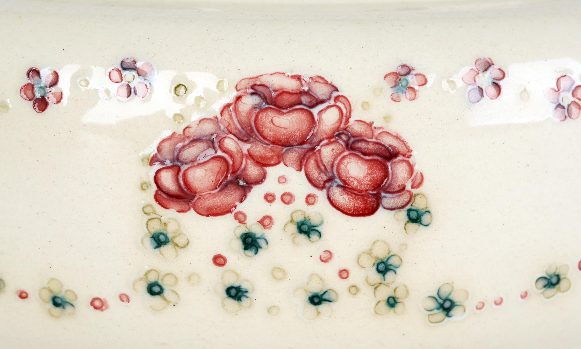 A stylish art pottery bowl made for Liberty & Co decorated with tube lined Forget Me Not’s and Rose’s forming garlands around the body of the bowl by William Moorcroft (British, 1872-1945) and dating from around 1913. William Moorcroft started out