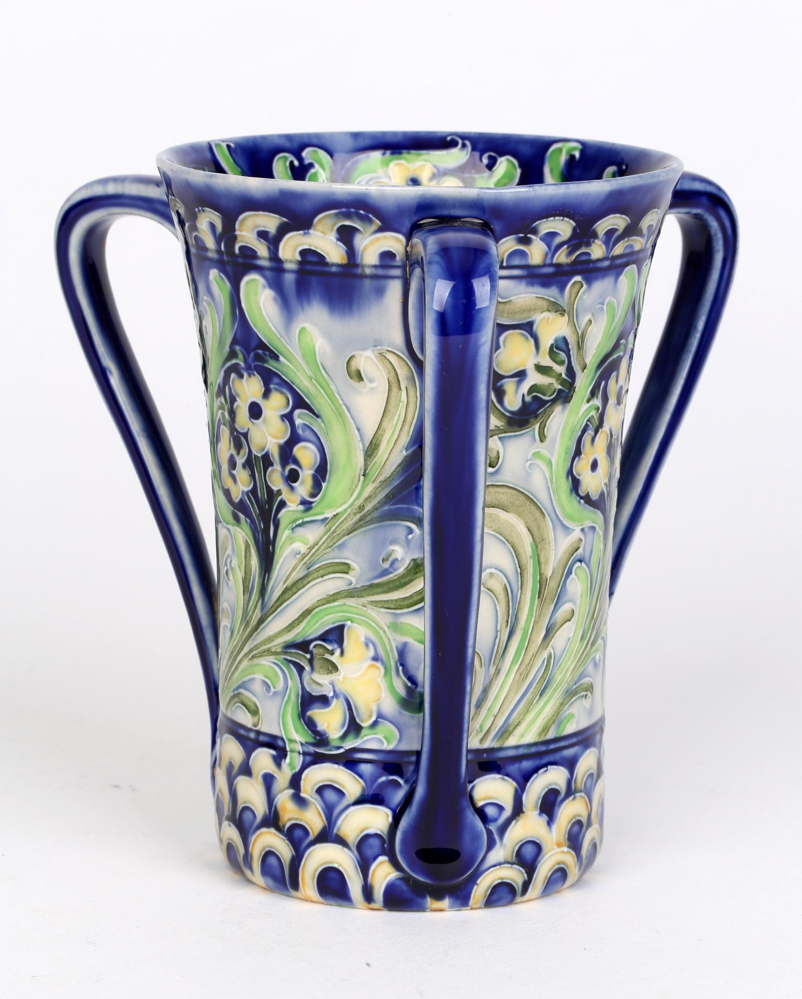 Art Nouveau James MacIntyre & Co. Florian Ware three-handled flared loving cup decorated with tube lined floral designs by William Moorcroft and dating from around 1900. William Moorcroft started out as a designer before becoming director of the art