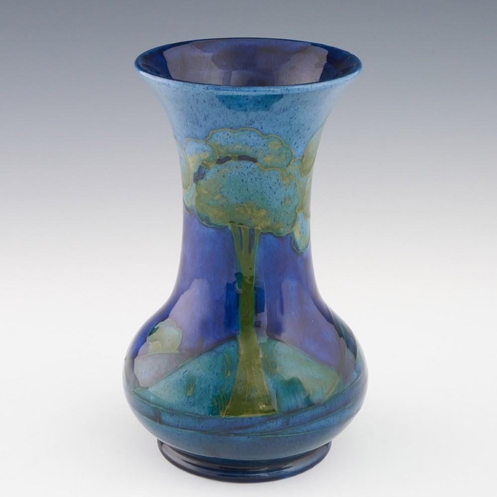Heading : William Moorcroft Moonlit Blue vase
Date : c1925
Origin : Burslem, England
Bowl Features : Baluster form with everted rim. Deep and pale blue with green depicting moonlit trees.
Marks : WM signature with stamped MOORCROFT MADE IN ENGLAND