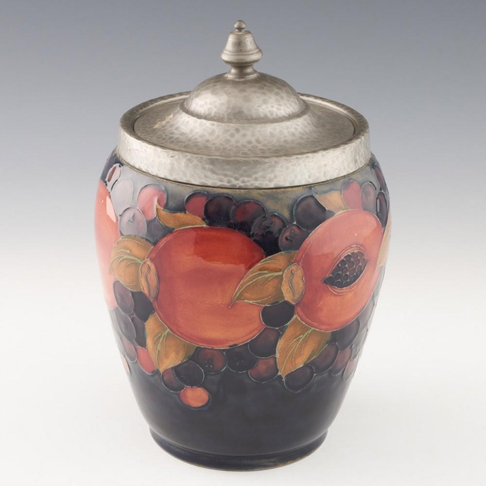 Heading : William Moorcroft Pomegranate pattern biscuit barrel
Date : c1930
Origin : Burslem, England
Bowl Features : Blue ground with polychrome pomegranate decoration - hammered pewter cover
Marks : Signed WM - stamped MOORCROFT MADE IN