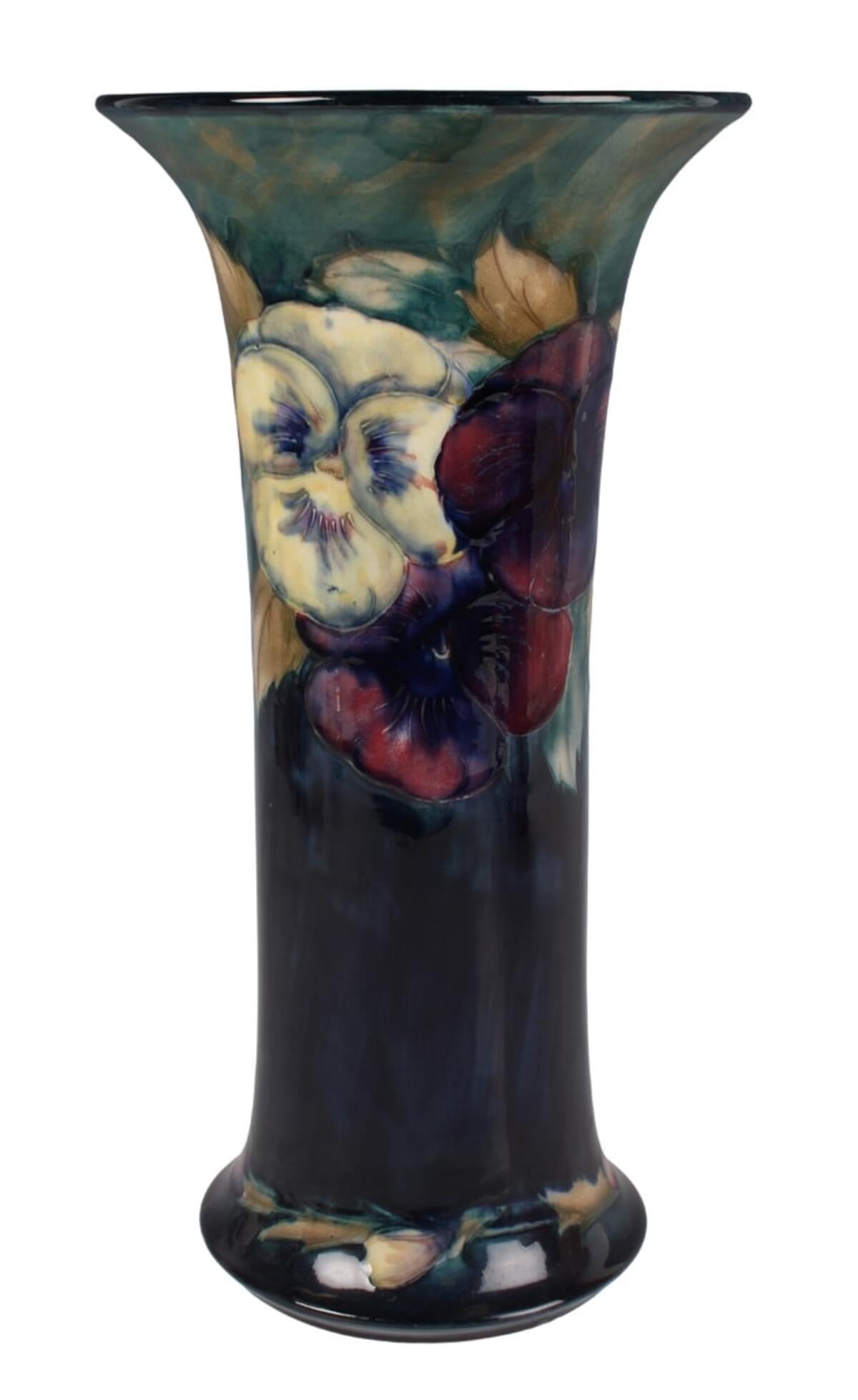 A Moorcroft Pottery Pansy pattern vase, circa 1920, of cylindrical shape with dark ground, impressed factory marks to base with green painted signature, height 13 inches