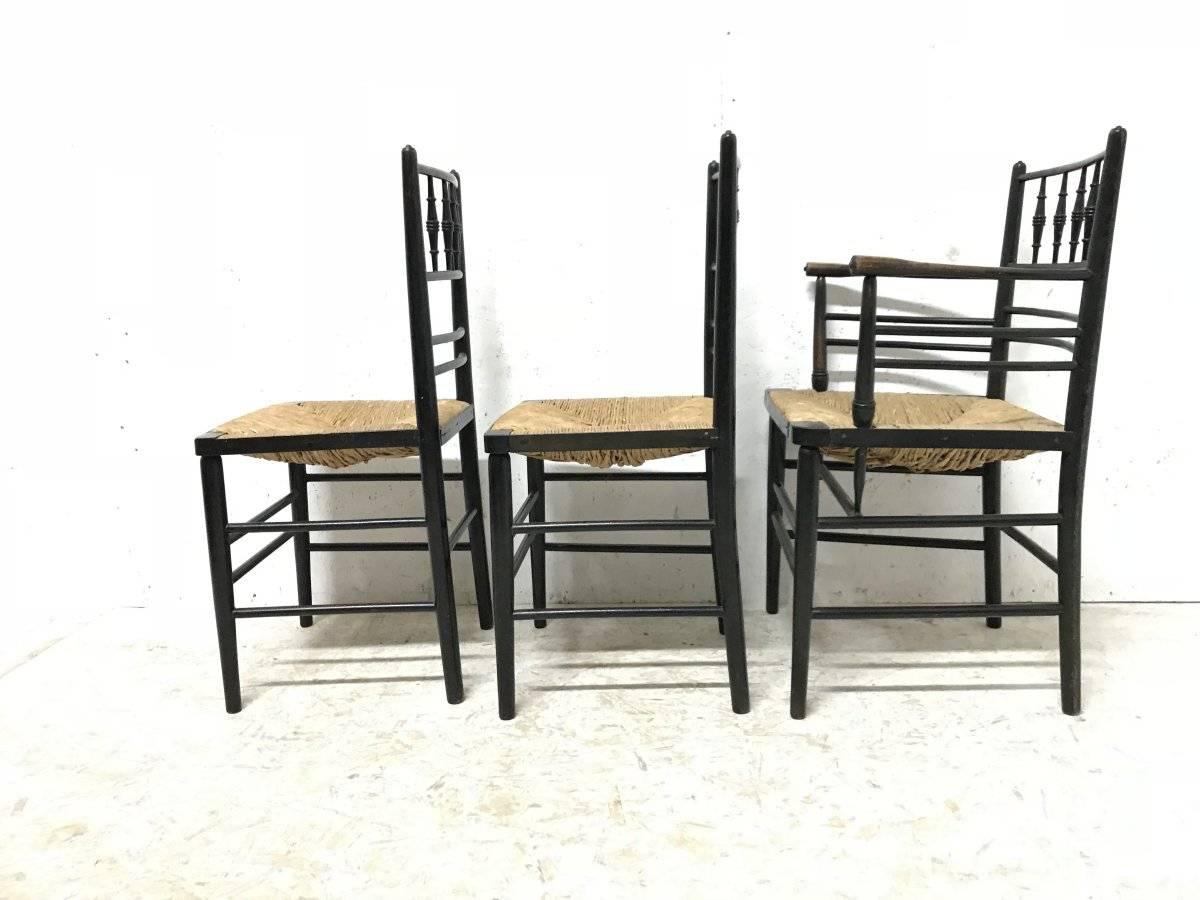 English William Morris, Five Ebonized Rush Seat Sussex Side Chairs and Matching Armchair