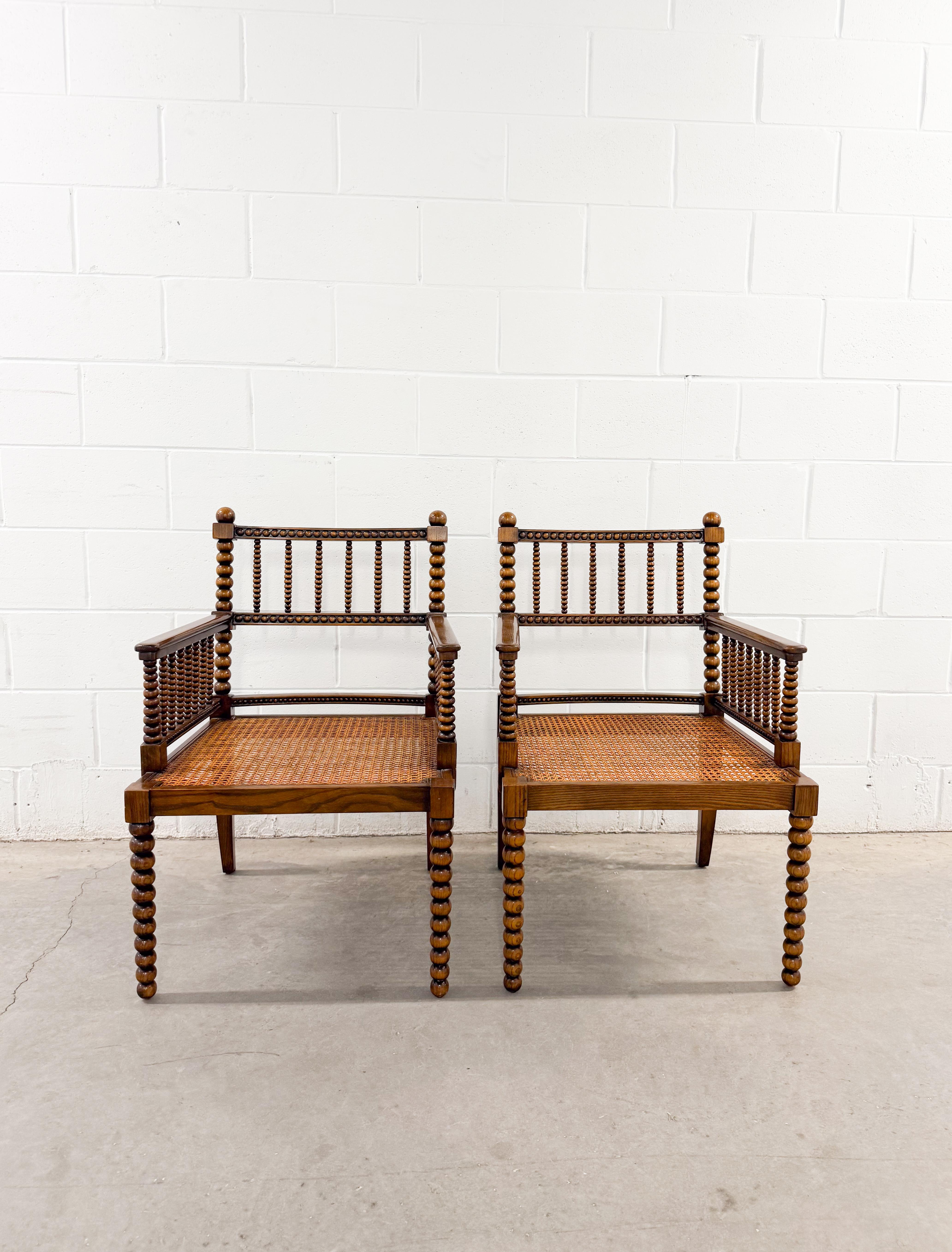 Un encantador par de sillones vintage torneados de bolillos, probablemente de mediados del siglo XX (1940-1970), presenta una encantadora mezcla de estilo histórico y construcción robusta. Estas sillas se inspiran en las elegantes sillas Bergère