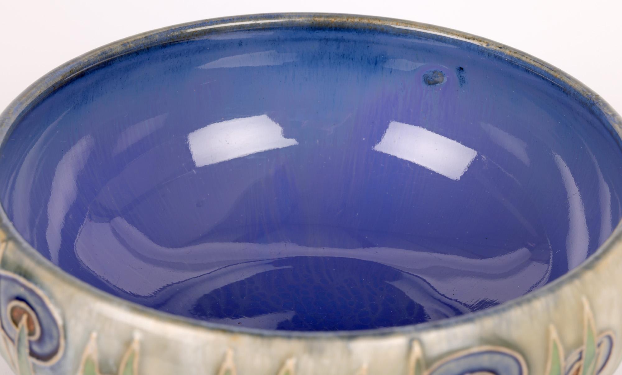 A stylish Doulton Lambeth art deco abstract floral design bowl by renowned artist William Rowe and dating from around 1920. The stoneware bowl is wide round shape standing on a narrow round salt glazed foot. The body of the bowl is decorated with