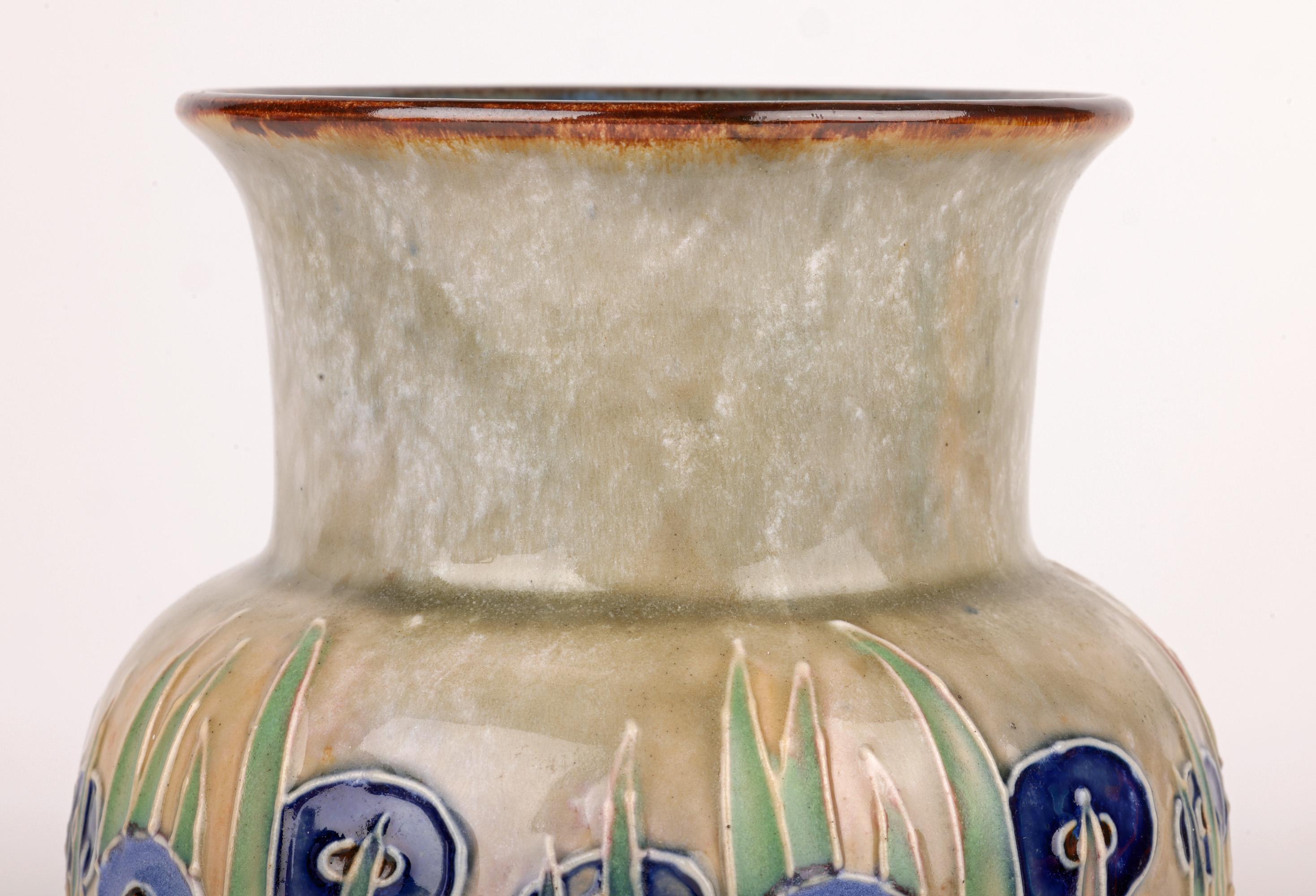 Rare et étonnant vase en poterie Doulton Lambeth Art Deco décoré de graminées fleuries bordées de tubes par l'artiste renommé et recherché William Rowe et datant d'entre 1924 et 1927. Le vase en grès a une forme bulbeuse large et repose sur un pied