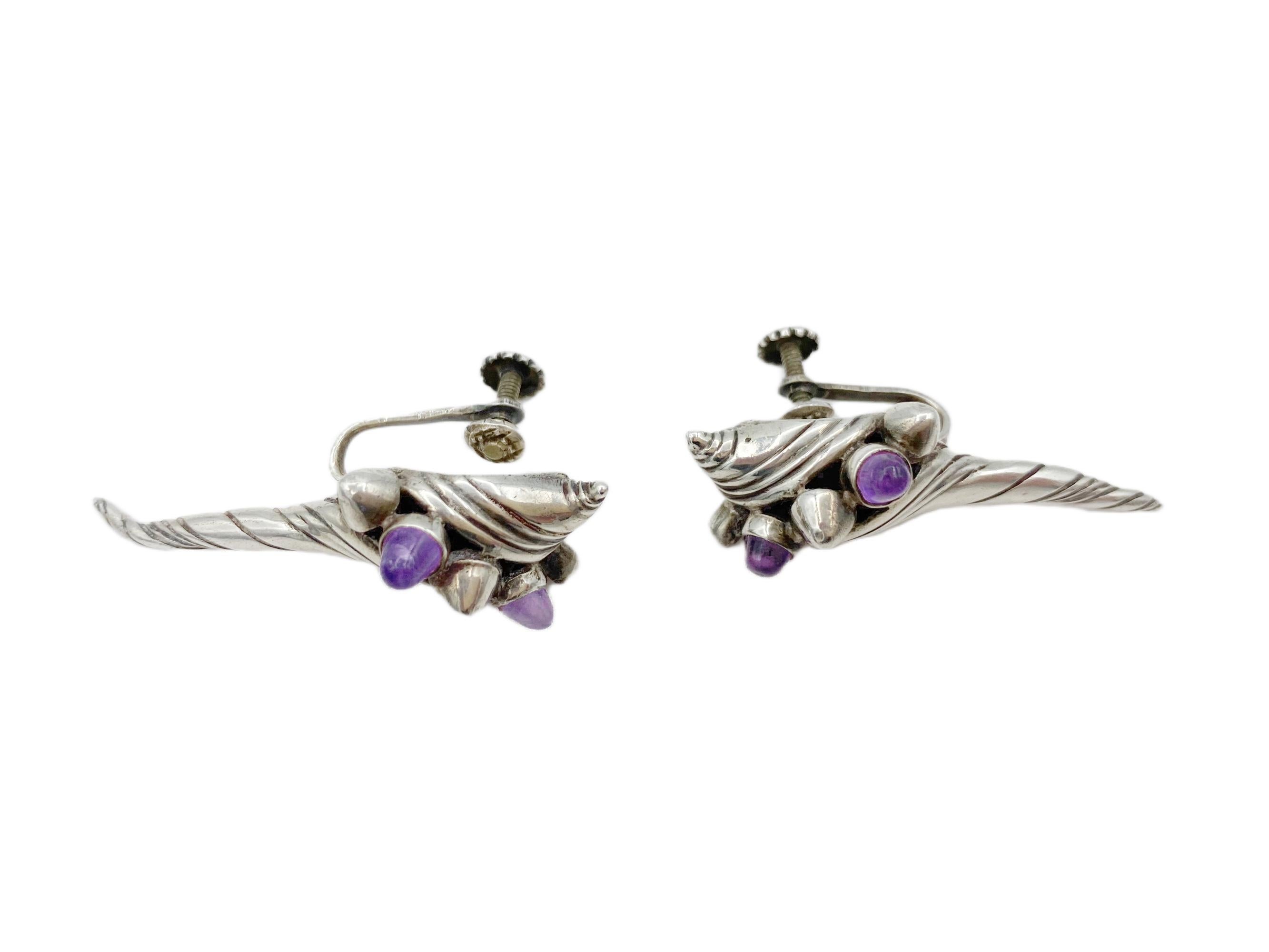 A rare and sculptural pair of sterling silver and amethyst earrings by William Spratling, Taxco, Mexico, circa the 1950s. Each earring is formed as a stylized spiral conch shell accented with rich amethyst cabochons, a motif that showcases