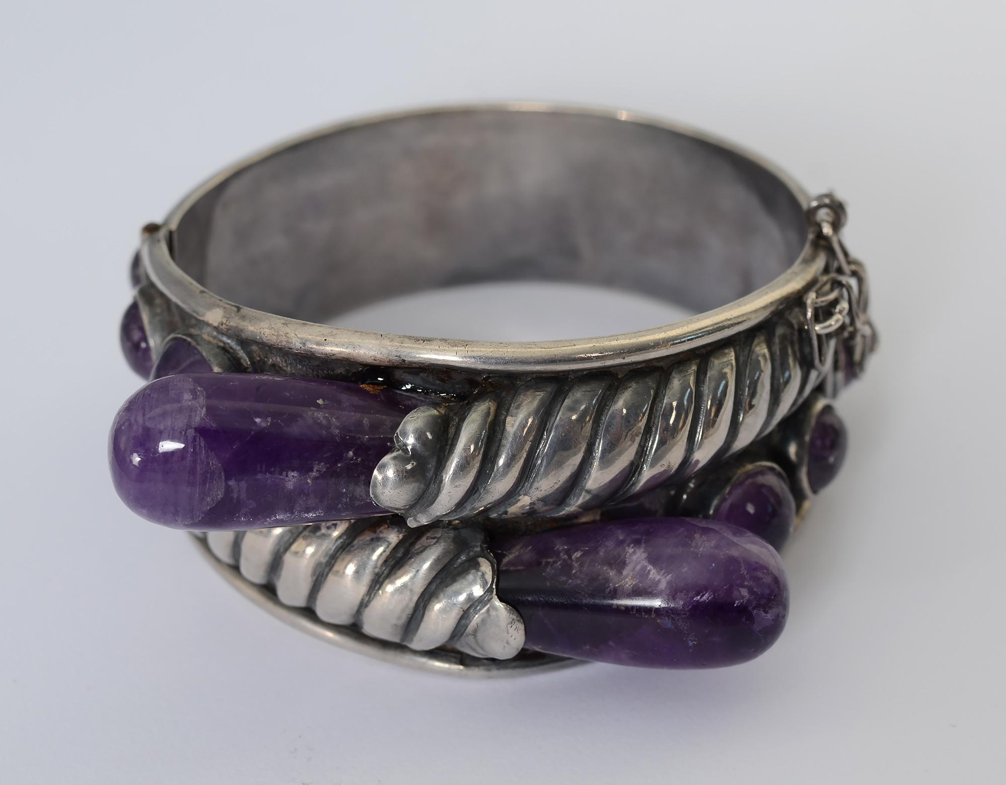 Rare, early sterling with amethyst bracelet by silver master, William Spratling. The bracelet has a raised, striated silver design throughout that terminates with two pear shaped cabochon amethysts. On either side of them are three graduated size