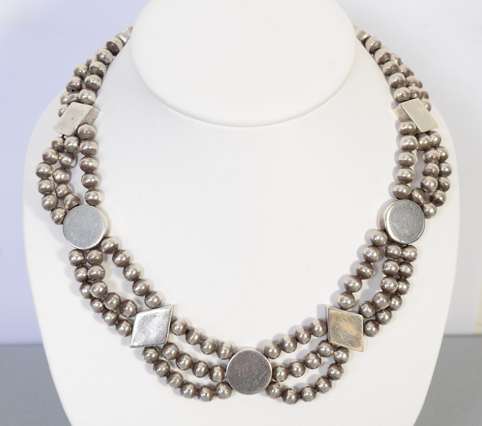 Unusual necklace by silver master, William Spratling in which he combined groups of beads with round discs and diamond shaped ornaments. The round discs are 11/16