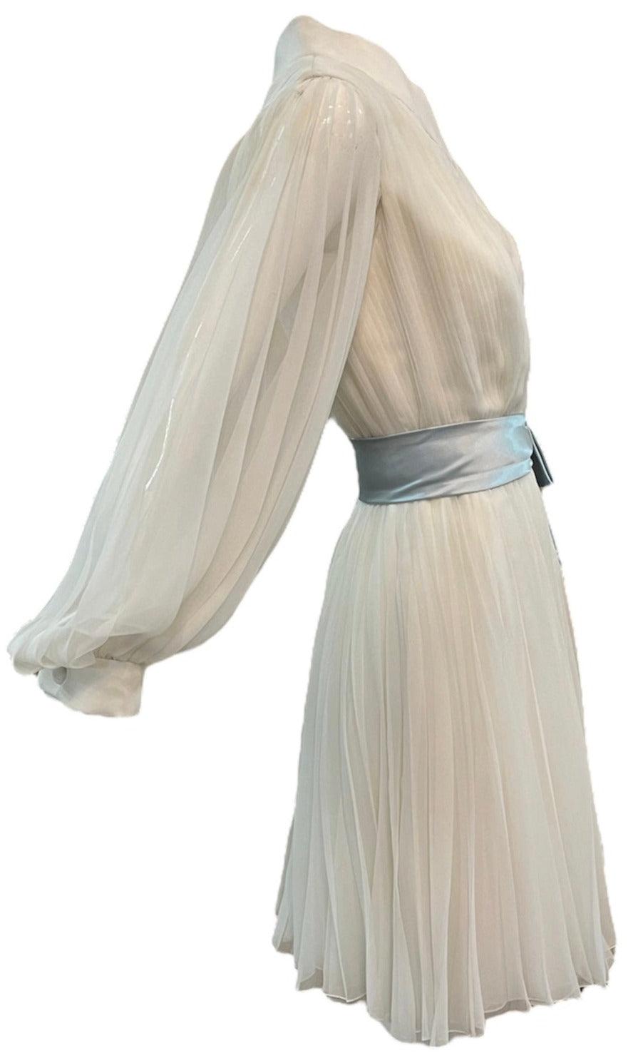 1960's white pleated dress by the great designer and Hollywood costumer, William Travilla, who designed some of the most iconic pieces in film history. This fully lined poly chiffon dress boasts a wide collar, balloon sleeves, and a full pleated