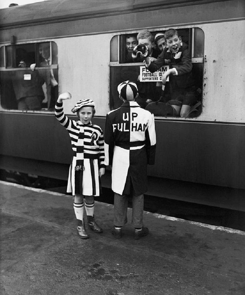 "Fan's Fashion" by William Vanderson

5th January 1957: Two young Fulham football fans Freda and Frank Hearn dressed in their club's colours of black and white, wait to board an 'Ipswich Special' at Addison Road station, London. Fulham are playing