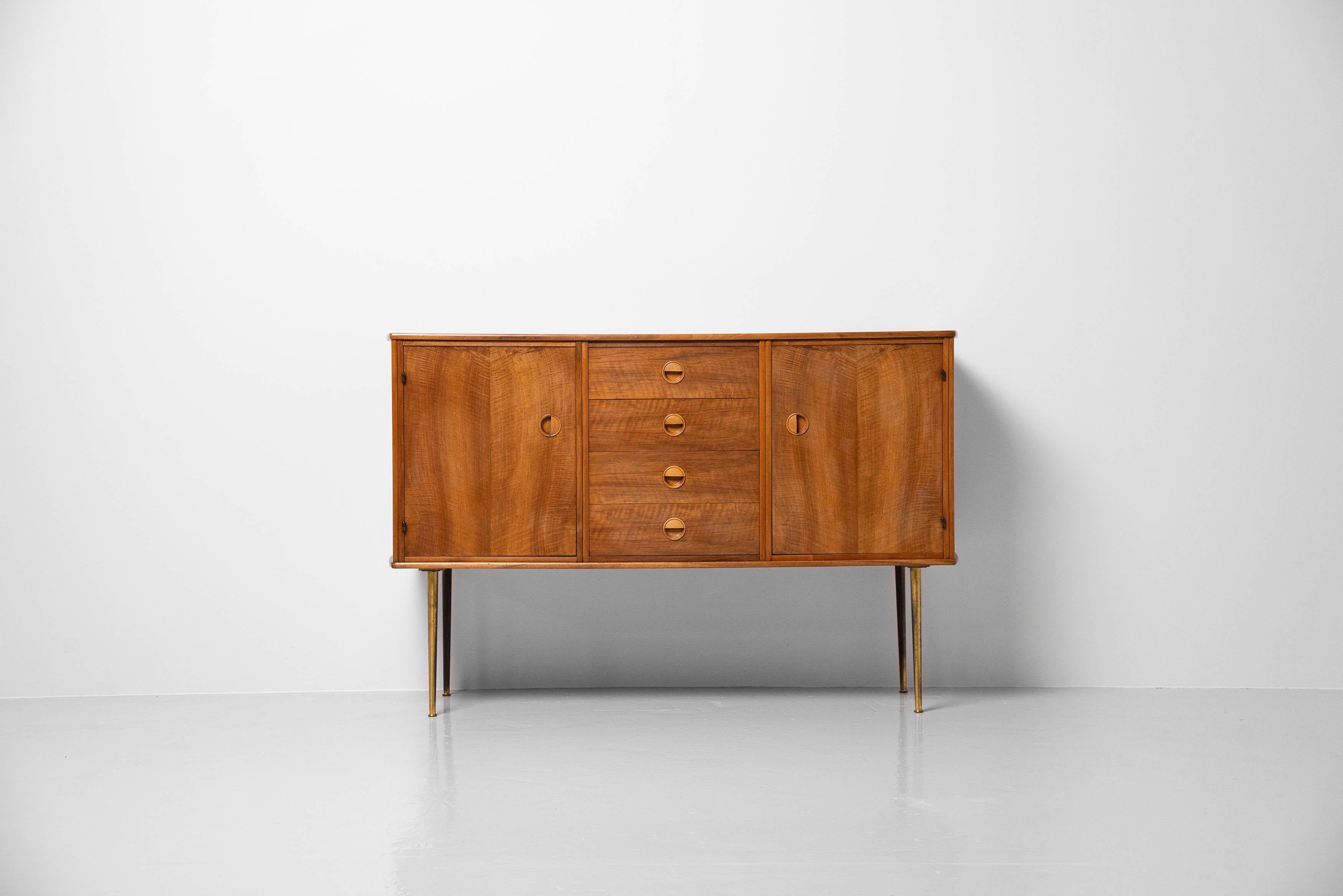 Very nice small and unusual high credenza designed by William Watting and and manufactured by Fristho Modernord, Holland 1956. This quality credenza has 2 folding doors on the left and right with a shelve behind and in the middle there are 4