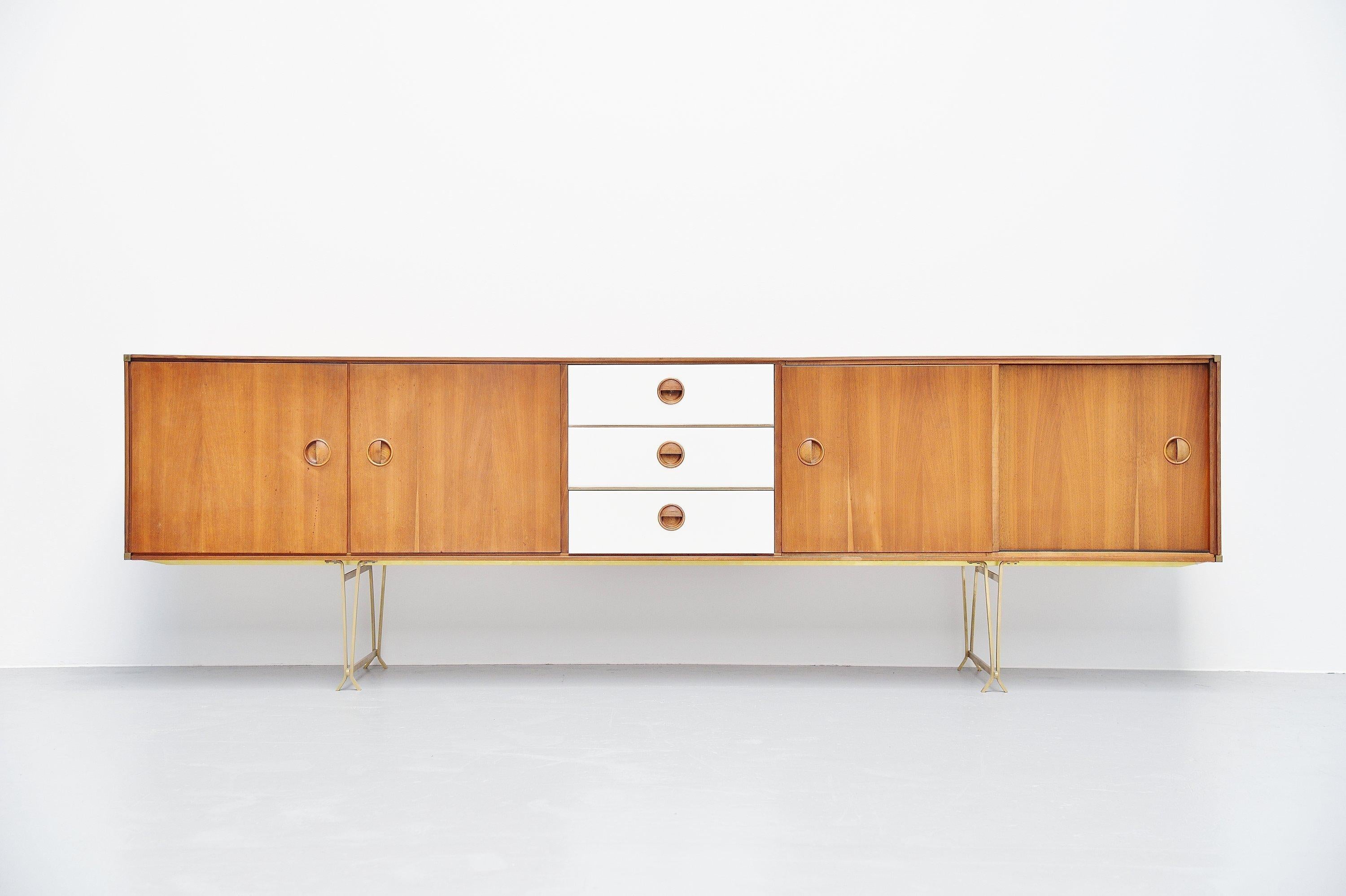 Superb long Minimalist sideboard designed by William Watting and manufactured by Fristho, Holland 1954. The credenza is made of teak wood and has brass details, corners, legs etc. The 3 drawers in the middle are white painted. On the left there are