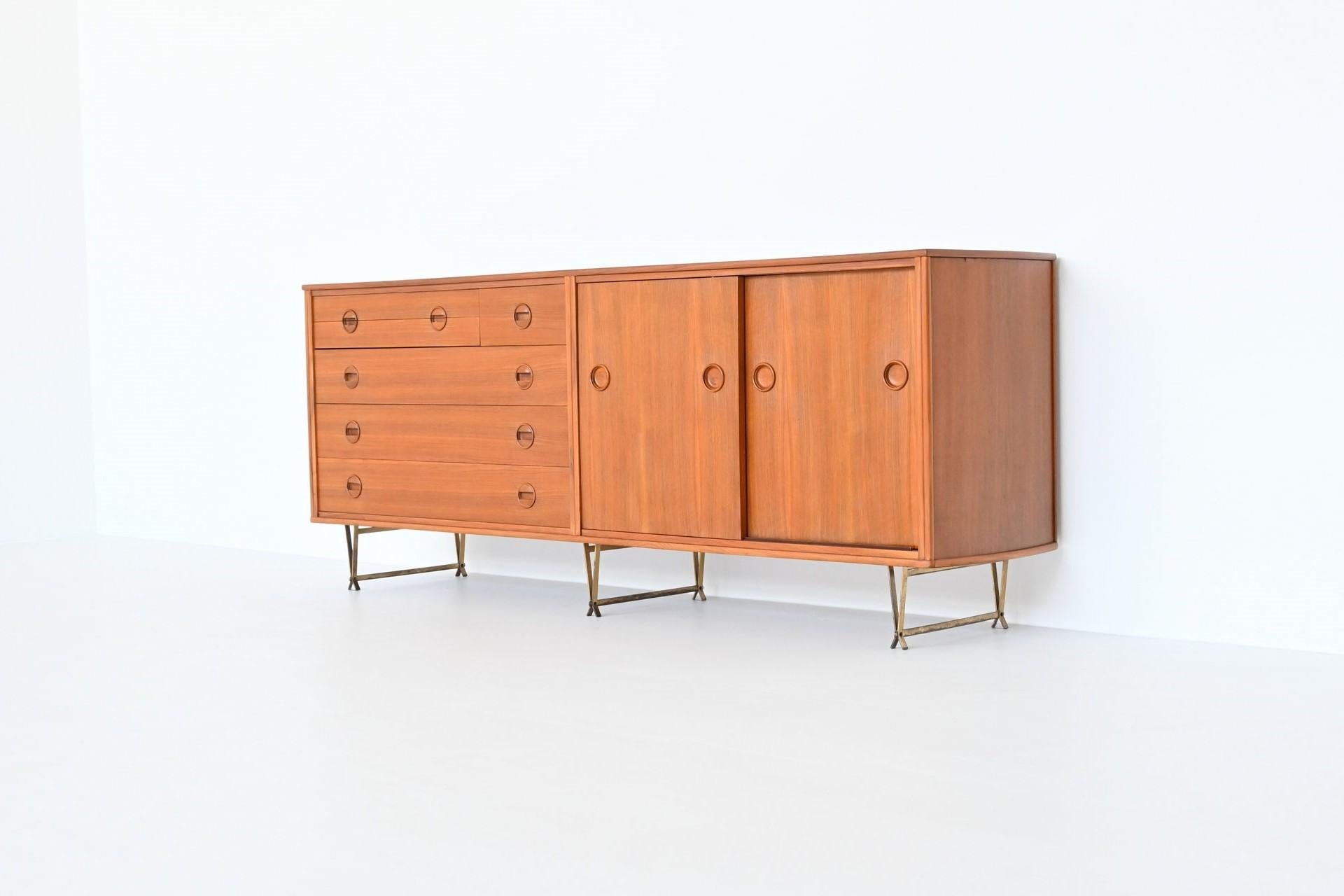 Stunning and rare sideboard designed by William Watting and manufactured by Fristho Franeker, The Netherlands 1954. This very nice shaped sideboard is made of veneered walnut wood with brass legs. On the right it has two sliding doors with shelves