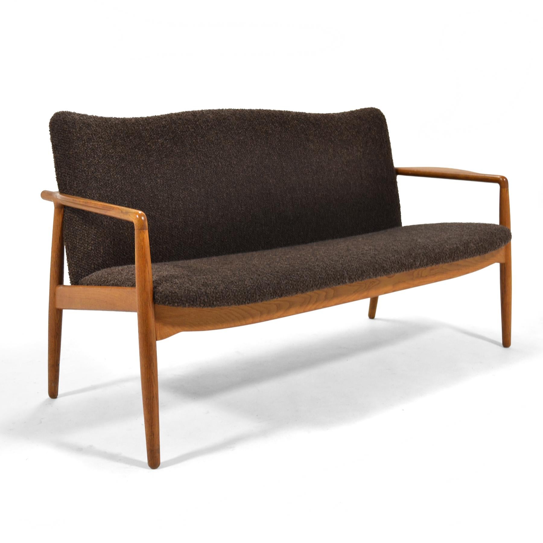 This lovely little settee by William Watting has an elegant frame carved of oak which supports a seat upholstered in a wonderful nubby brown fabric. Like so much post-war Scandinavian design, it obviously owes a debt to Finn Juhl and his innovation