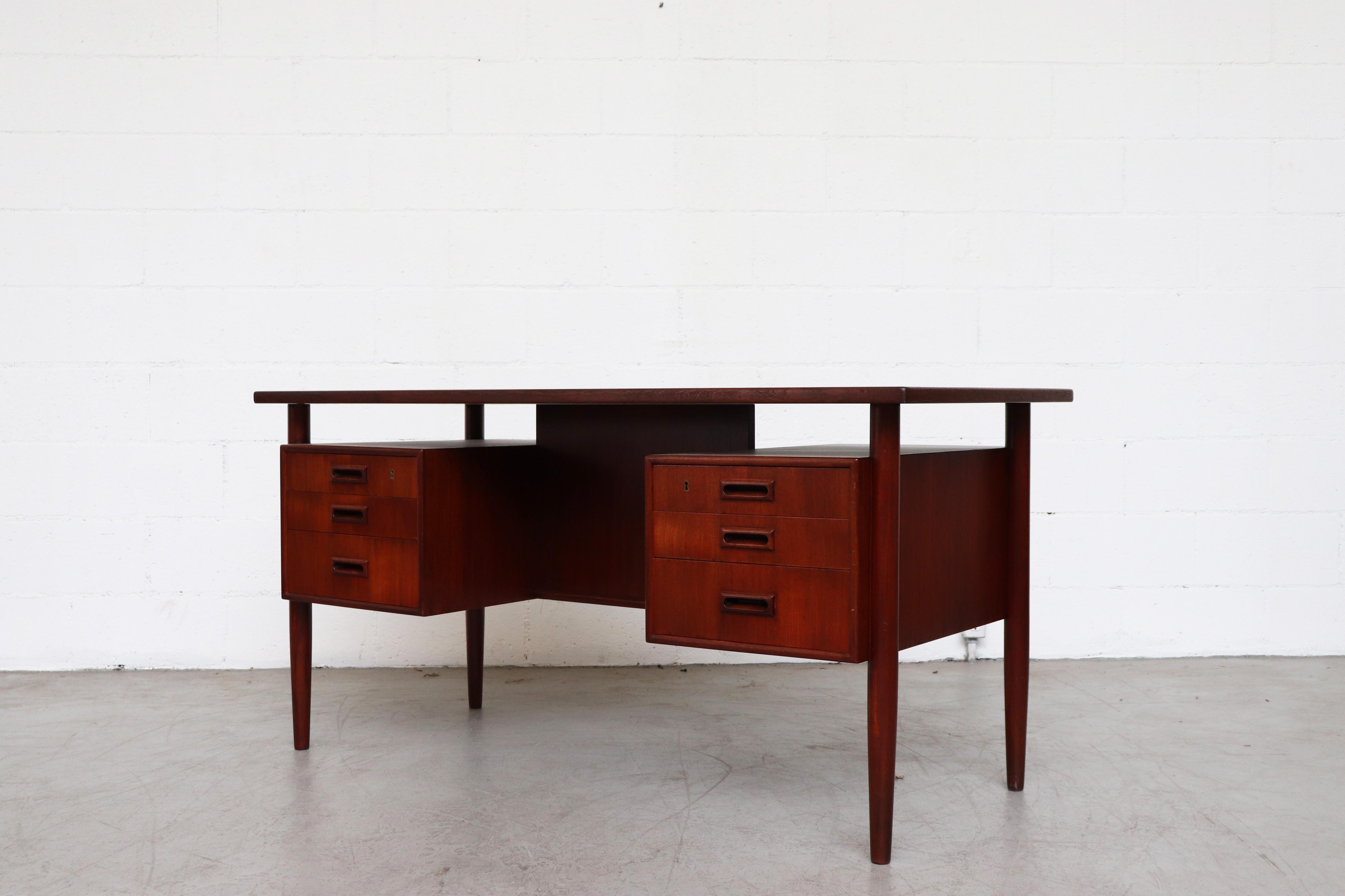 William Watting style teak desk with six drawers, floating top, and bookshelf cubbies on the back side. In original condition with some signs of wear consistent with its age and usage.