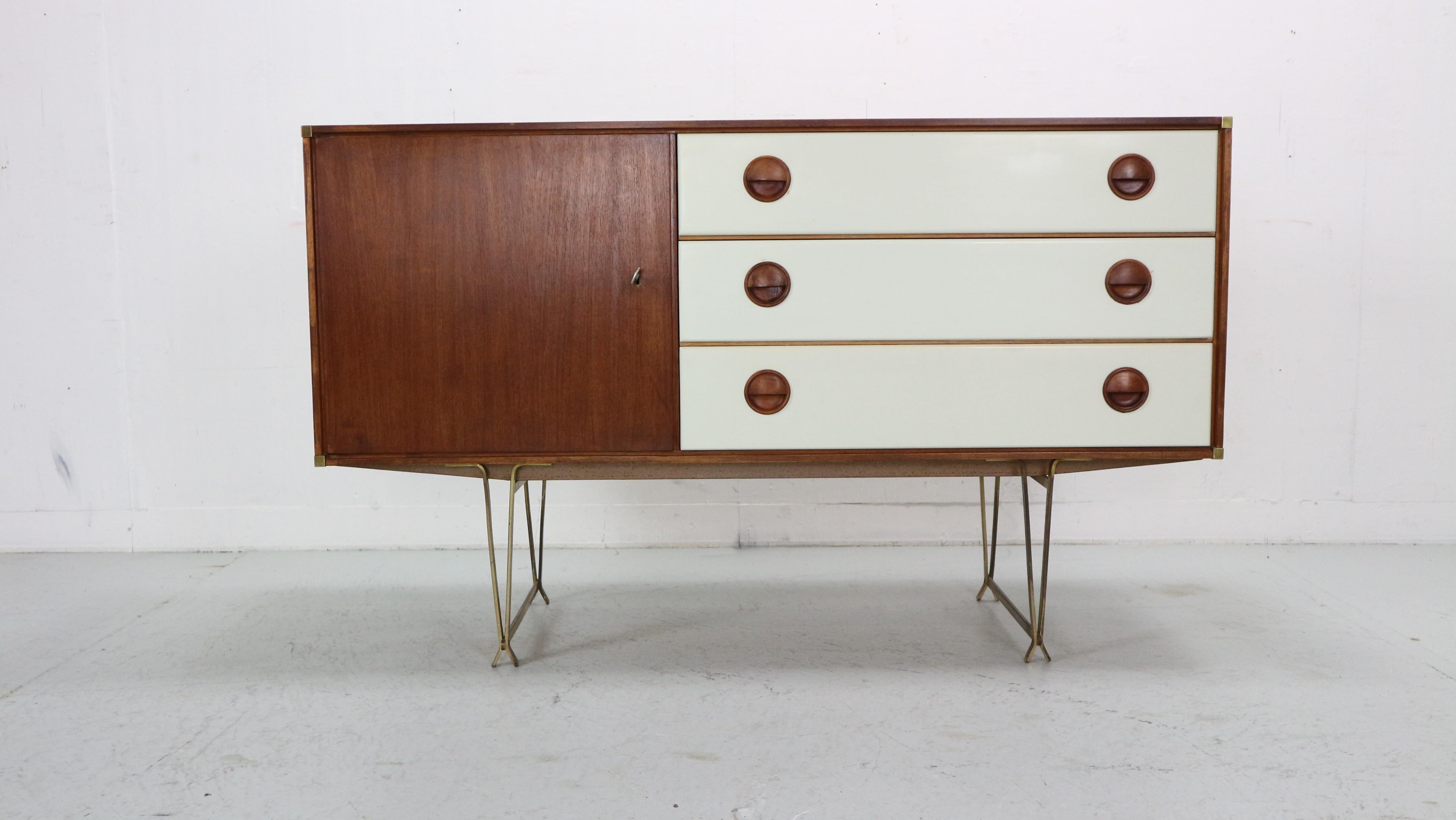 William Watting for Fristho, sideboard, teak, brass, lacquered wood, The Netherlands, 1950s. 

Elegant lacquered wooden sideboard with teak top and brass detailing. Very slim tapered brass legs that come together in two triangle shapes that makes