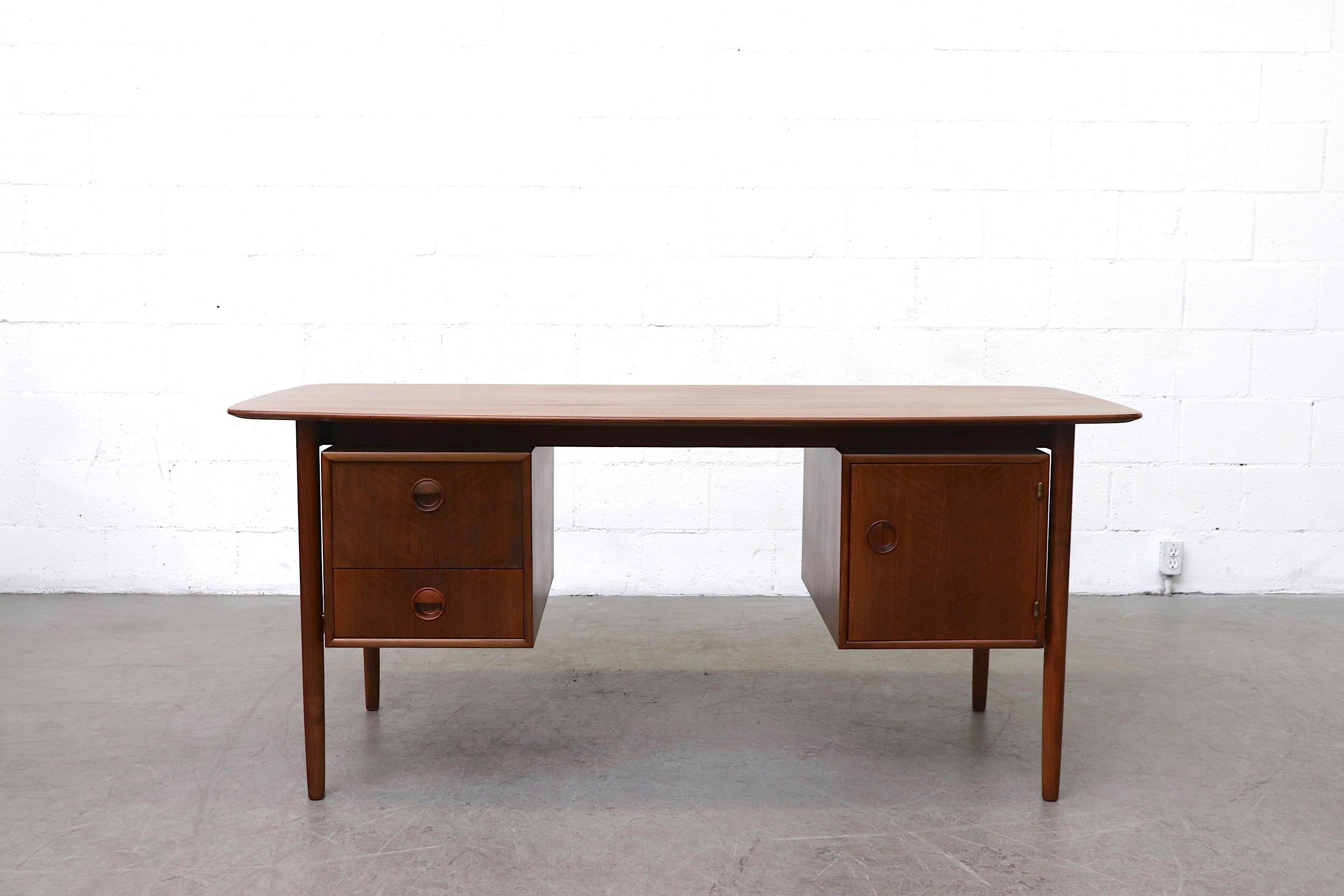 Midcentury William Watting teak writing desk. Pull-down storage and sliding drawers with organically carved hand pulls. In original condition with wear consistent with its age and usage.