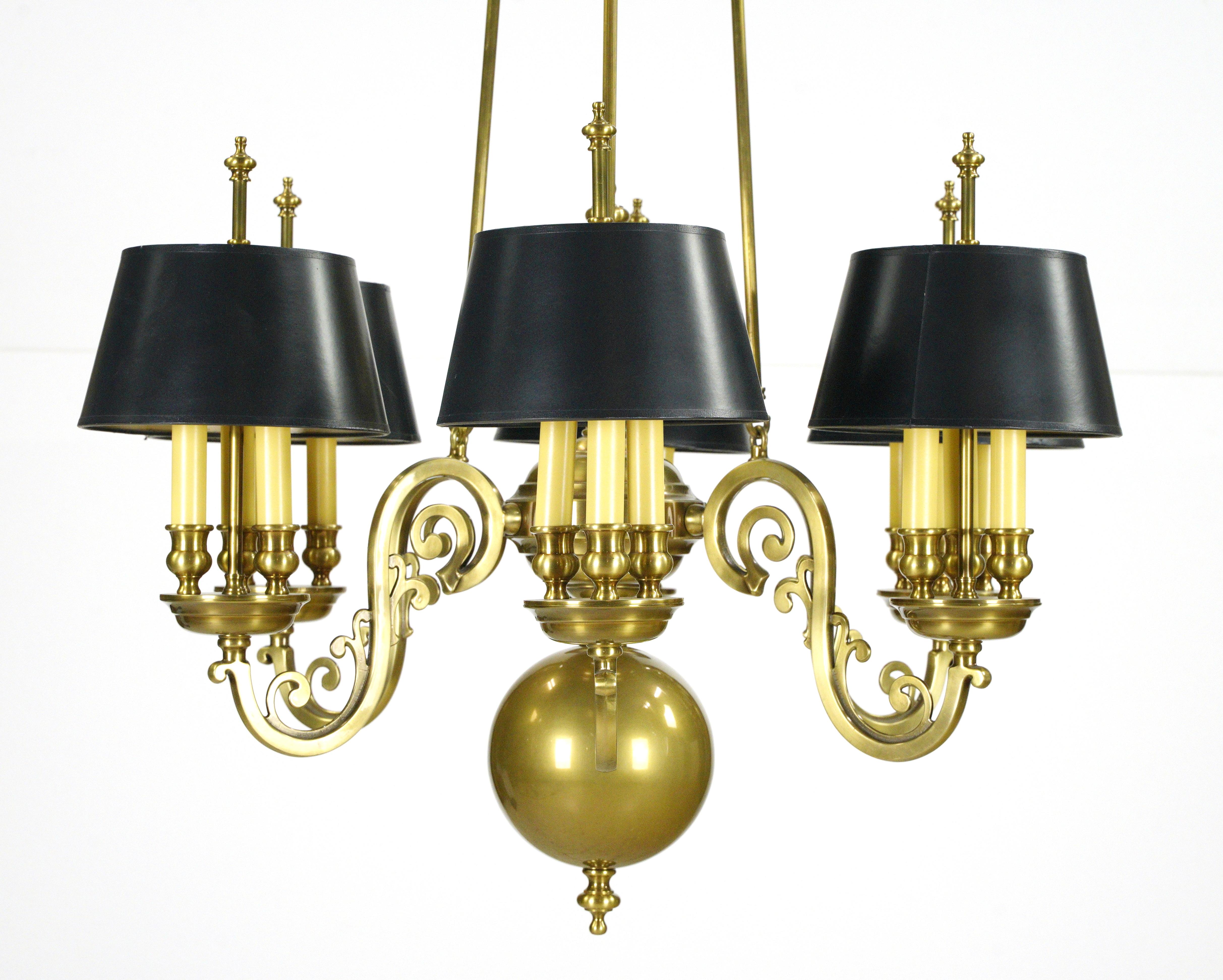 Williamsburg style chandelier with a brass patina frame and six arms featuring black shades positioned on three candle sticks. Good condition with minor surface wear on the brass. This light requires 18 candelabra light bulbs. Cleaned and restored.