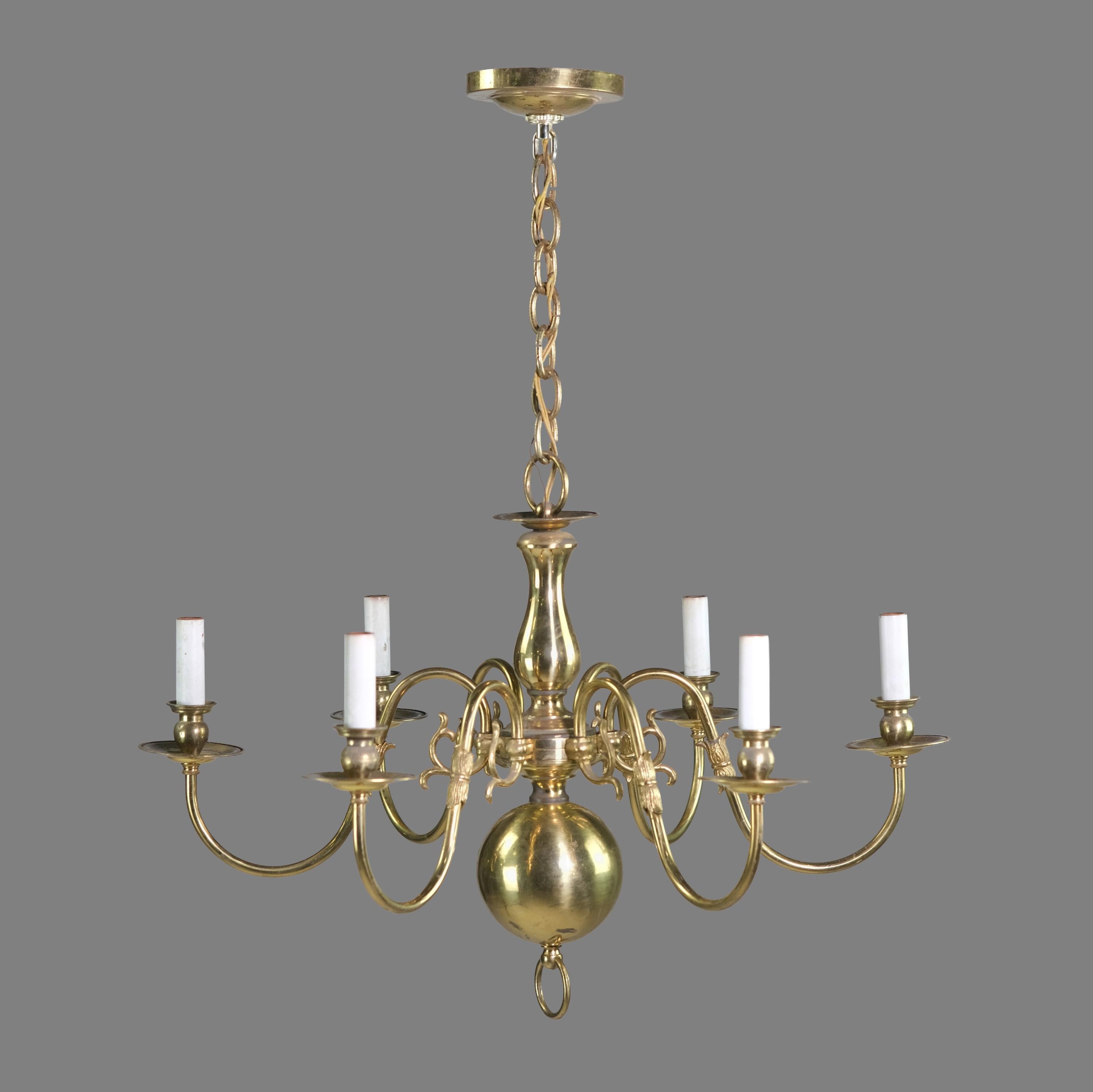 20th century Colonial Williamsburg style chandelier done in a polished finish. Features subtle ornate swirl details on its six arms. Takes six standard household medium base lightbulbs. Cleaned and restored. Please note, this item is located in our