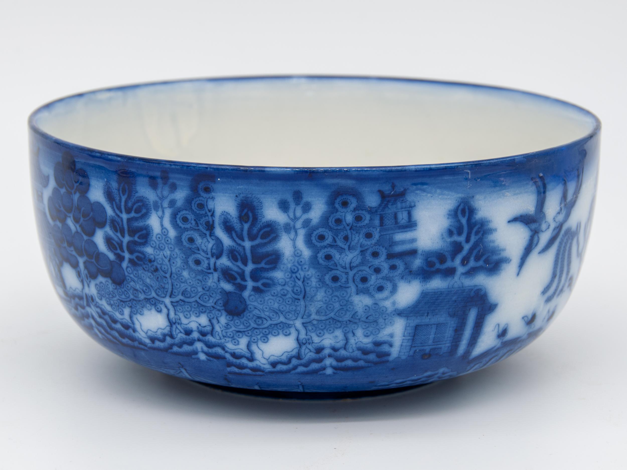 Decorative willow flow blue bowl. This design featured pagodas, trees, and birds. Flow blue is a style popular in Regency England that gets its name from the blue glaze applied, which gives the appearance of a flowing blue color on the design. This