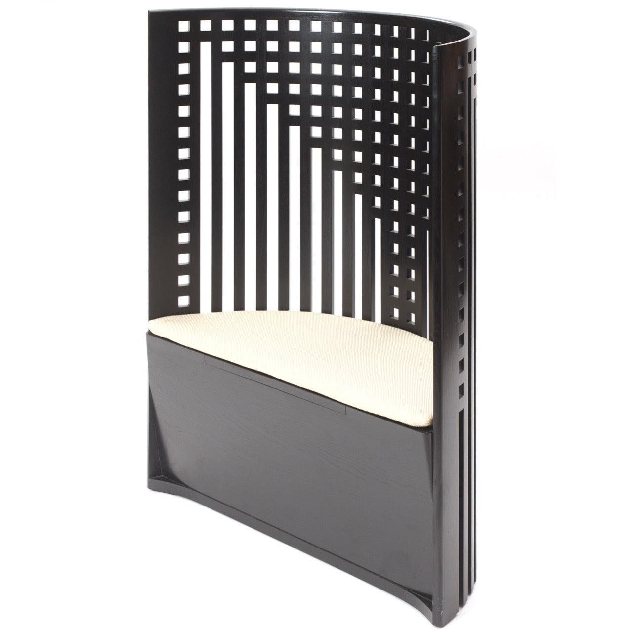 A small settee or large chair with a curved back having an abstracted geometric design that evokes the pattern of a willow tree, originally created by Charles Rennie Mackintosh for the Willow Tea Room in Glasgow, Scotland in 1902 and later