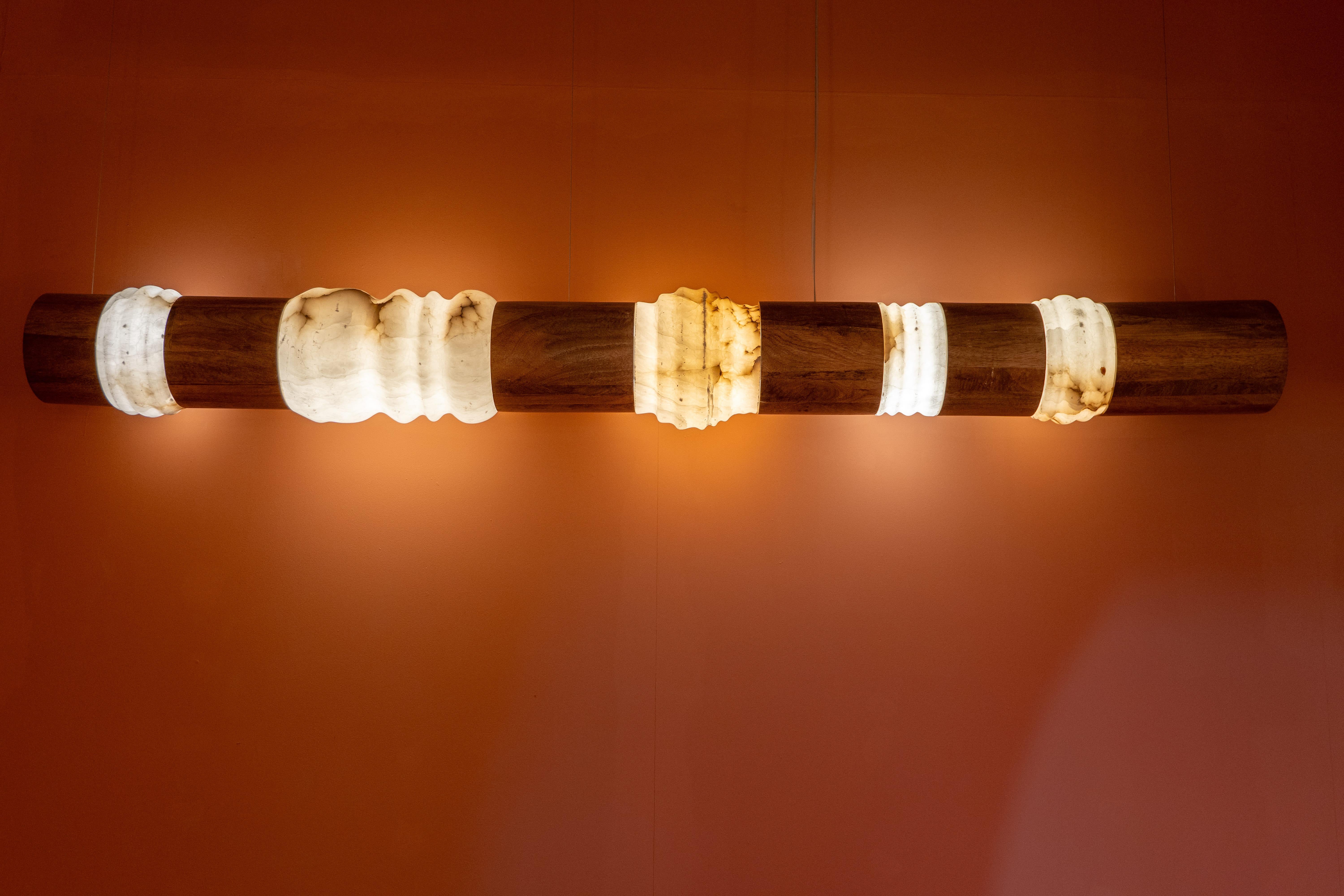 Ajoutez une touche audacieuse mais élégante à votre espace avec cette lampe murale sculpturale, fabriquée avec un mélange harmonieux de bois naturel et de pierre translucide. Conçue pour captiver, cette pièce d'éclairage horizontale présente une