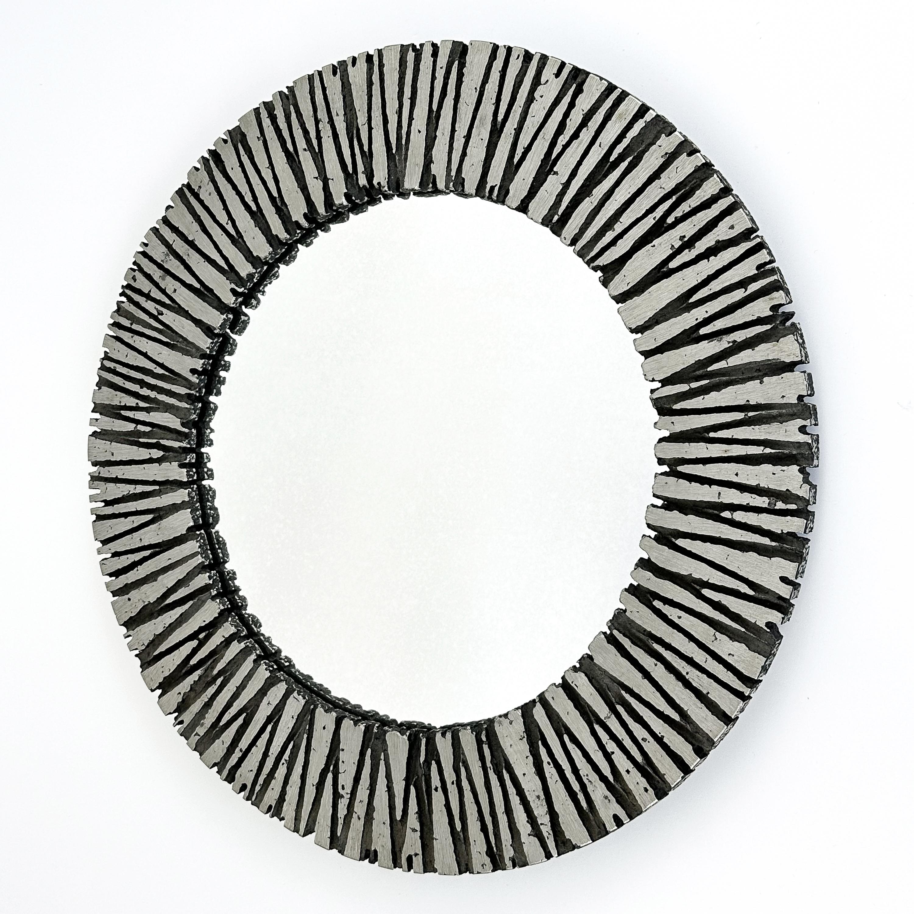 Ce miroir mural rond brutaliste de Willy Ceysens (1929-2007) est un exemple frappant du design innovant et de l'artisanat qui ont caractérisé les années 1960. Originaire de Belgique, l'œuvre est encadrée en aluminium massif, un matériau que Ceysens,