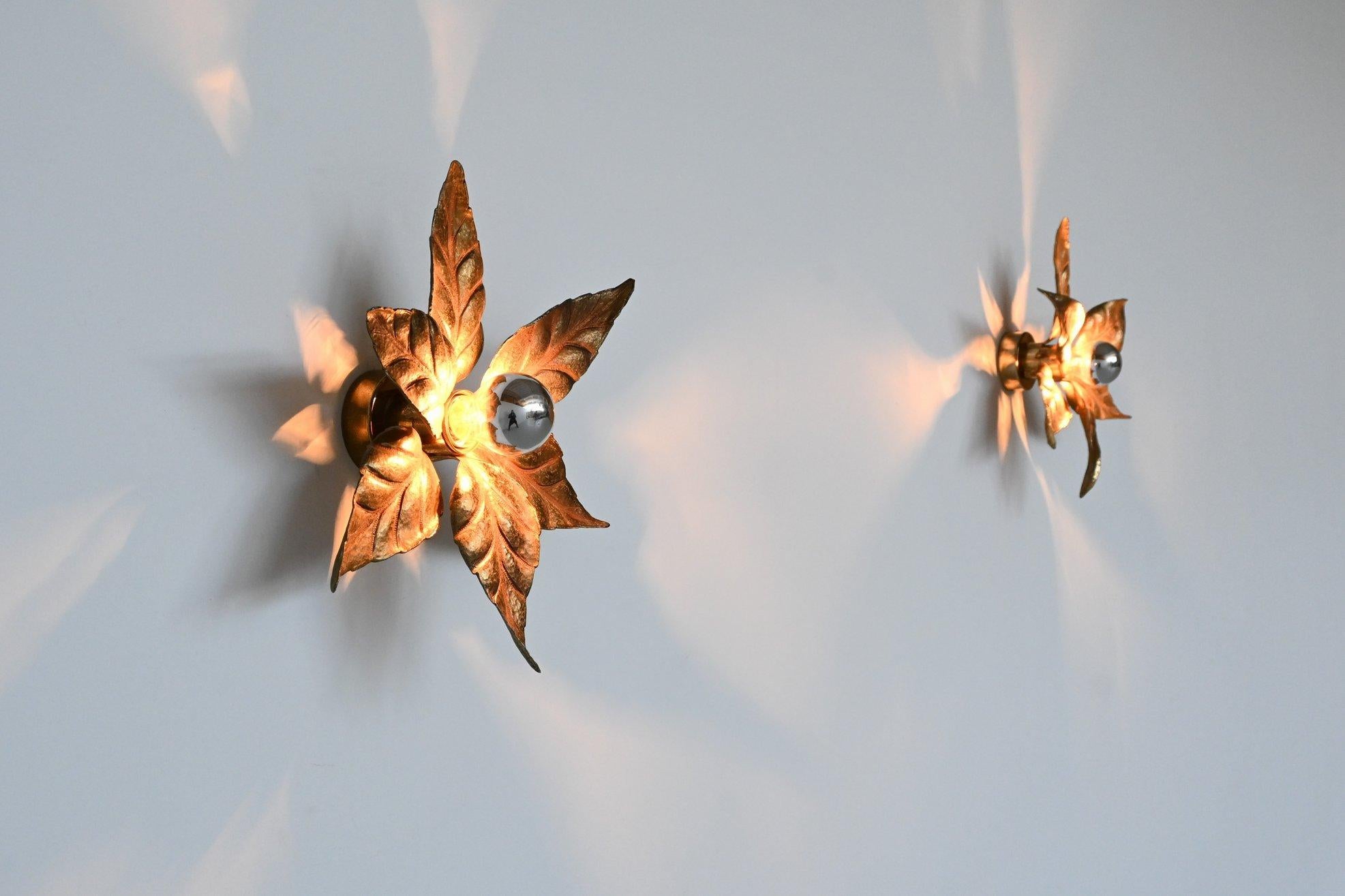 Beautiful pair of flower shaped sconces attributed by Willy Daro and manufacturer by Massive, Belgium 1960. These sculptural Hollywood Regency style lamps are made of gilt brass and have six textured leaves on a bar and circular base of the same