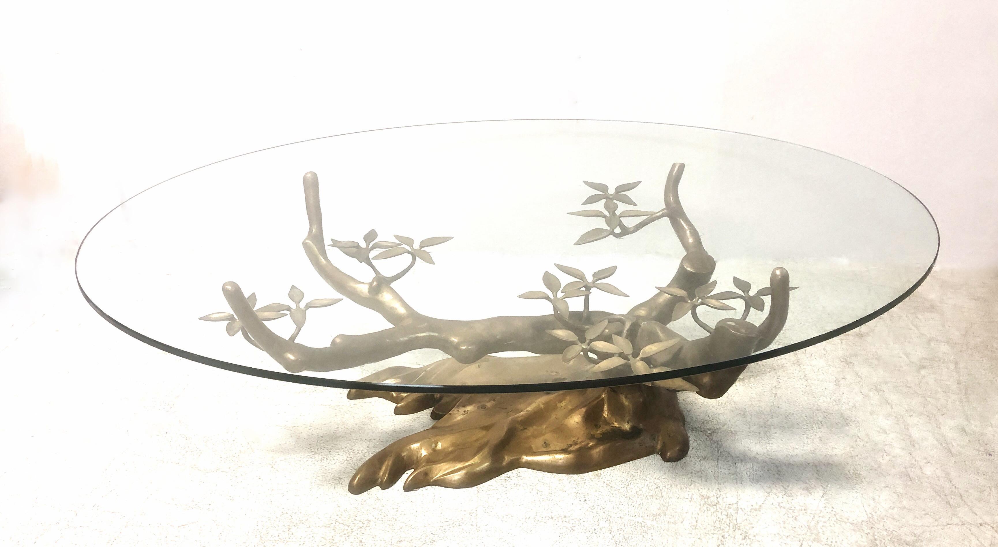 A brass coffee table in the shape of a stylized bonsai tree. Graceful with a simple elegance elegant design. Shown with the original oval glass top. Sculptural brass base is 38
