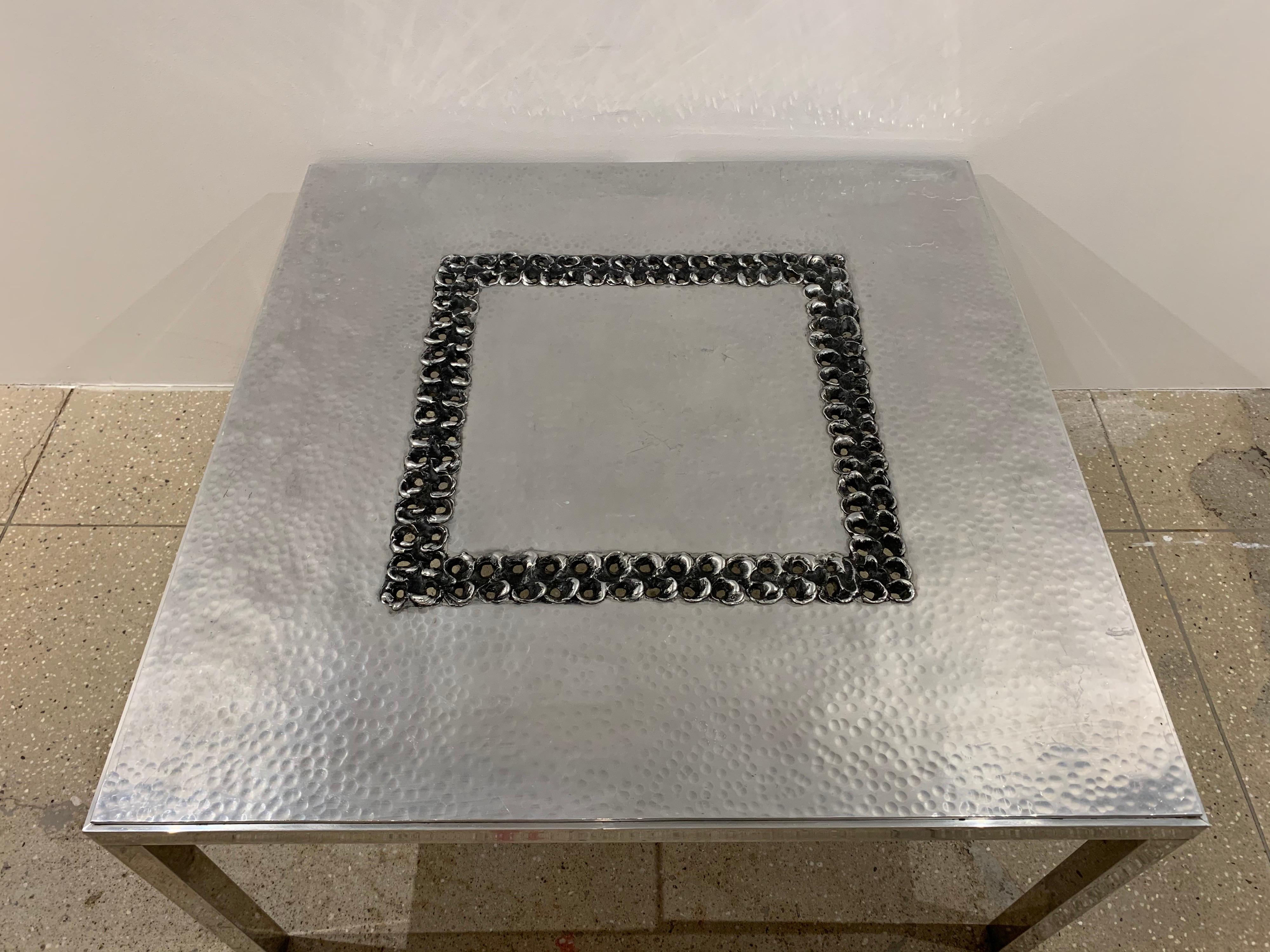 A handmade hammered and burnished aluminum coffee table by Belgian artist , Willy Luyckx for Aluclair.

Willy Luyckx was a goldsmith who worked for goldsmith Camille Colruyt before starting his own business in the 1960s. He also had an art center