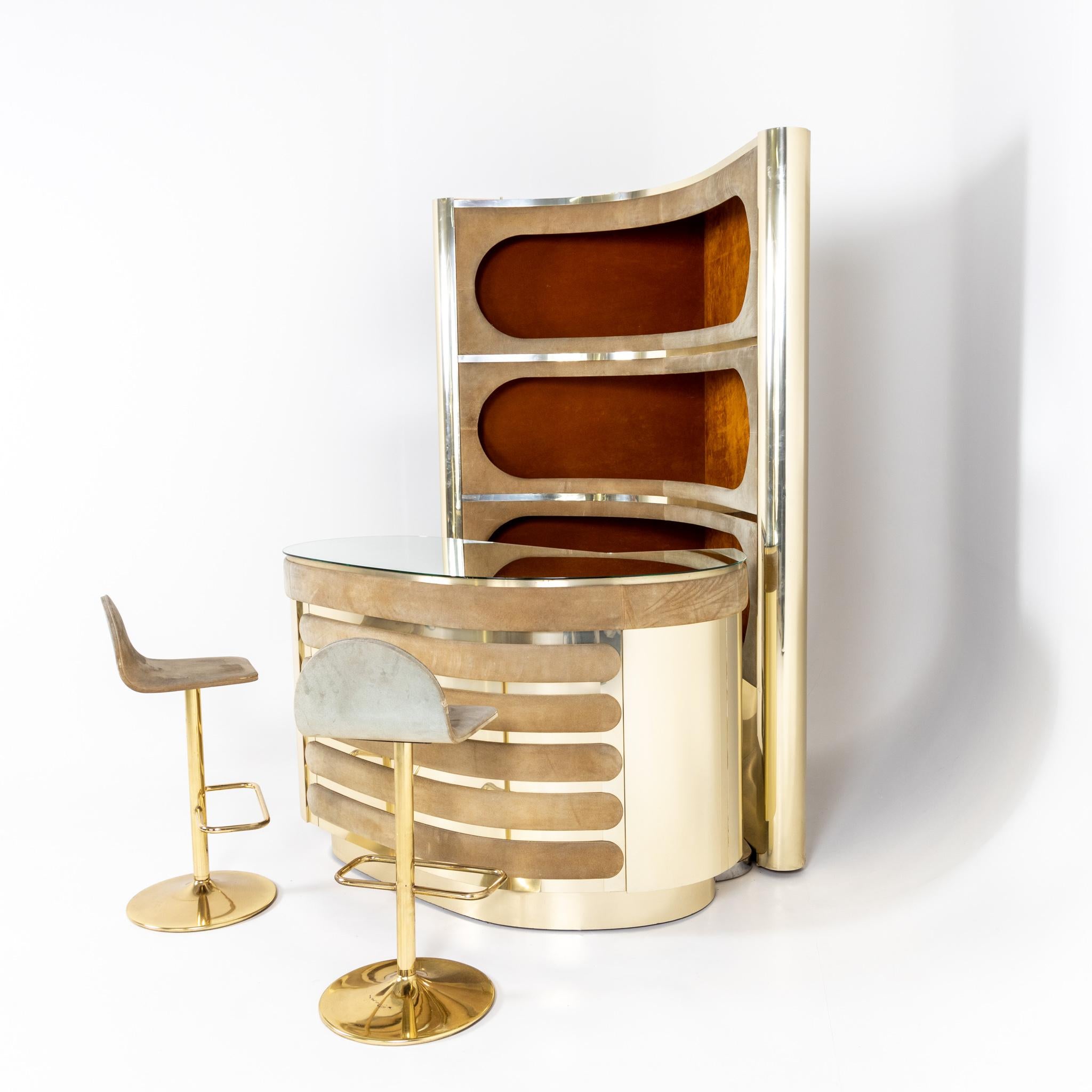 Large kidney-shaped bar with rear shelf and two bar stools. The chromed elements are interrupted by longitudinal oval panels covered with velvet.
Dimensions:
Counter: 88 x 128 x 82 cm
Shelf: 193 x 120.5 x 94 cm
Bar stool 83 x 38 x 37 x 63 cm.