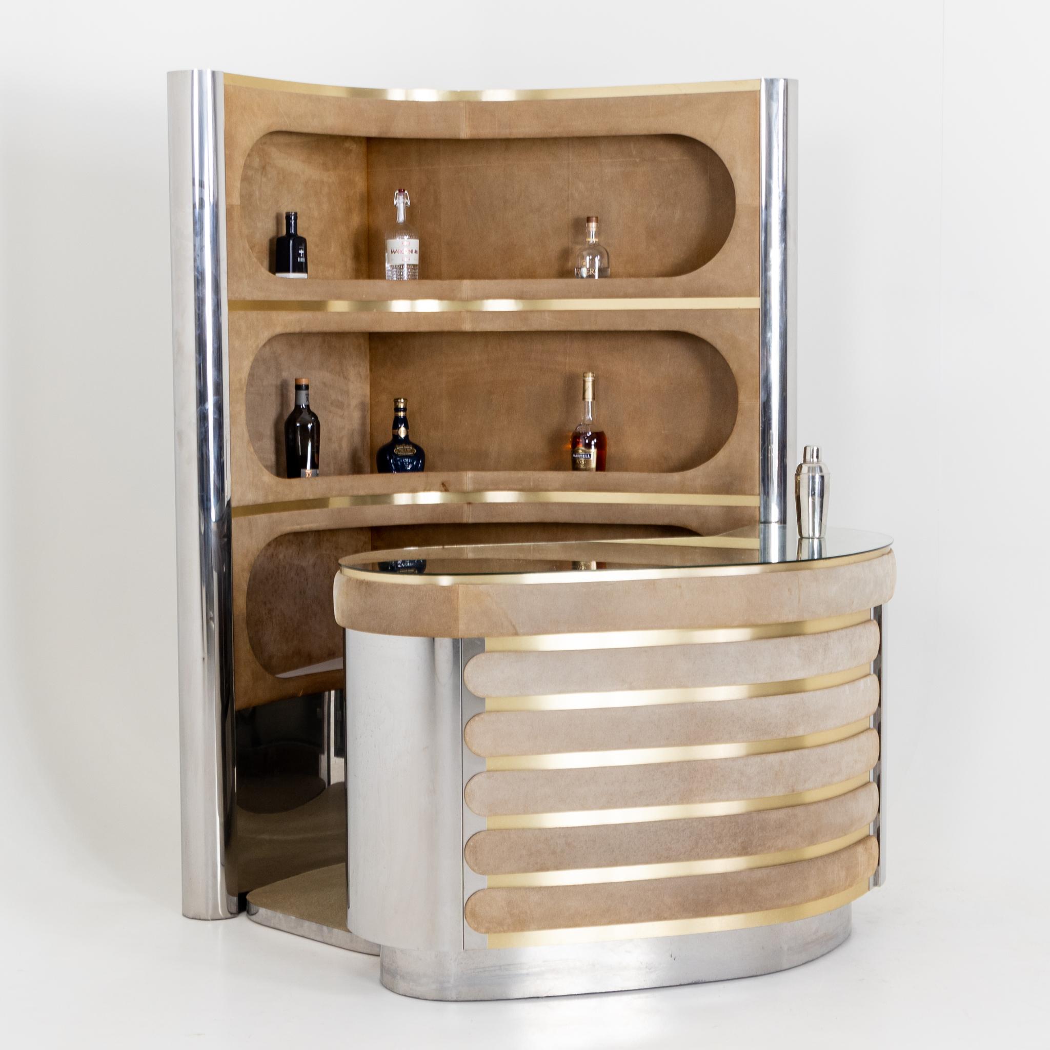 Large kidney-shaped bar with rear shelf. The chromed elements are interrupted by longitudinal oval panels covered with velvet.
Dimensions:
Counter: 88 x 128 x 82 cm.
Shelf: 193 x 120.5 x 94 cm.