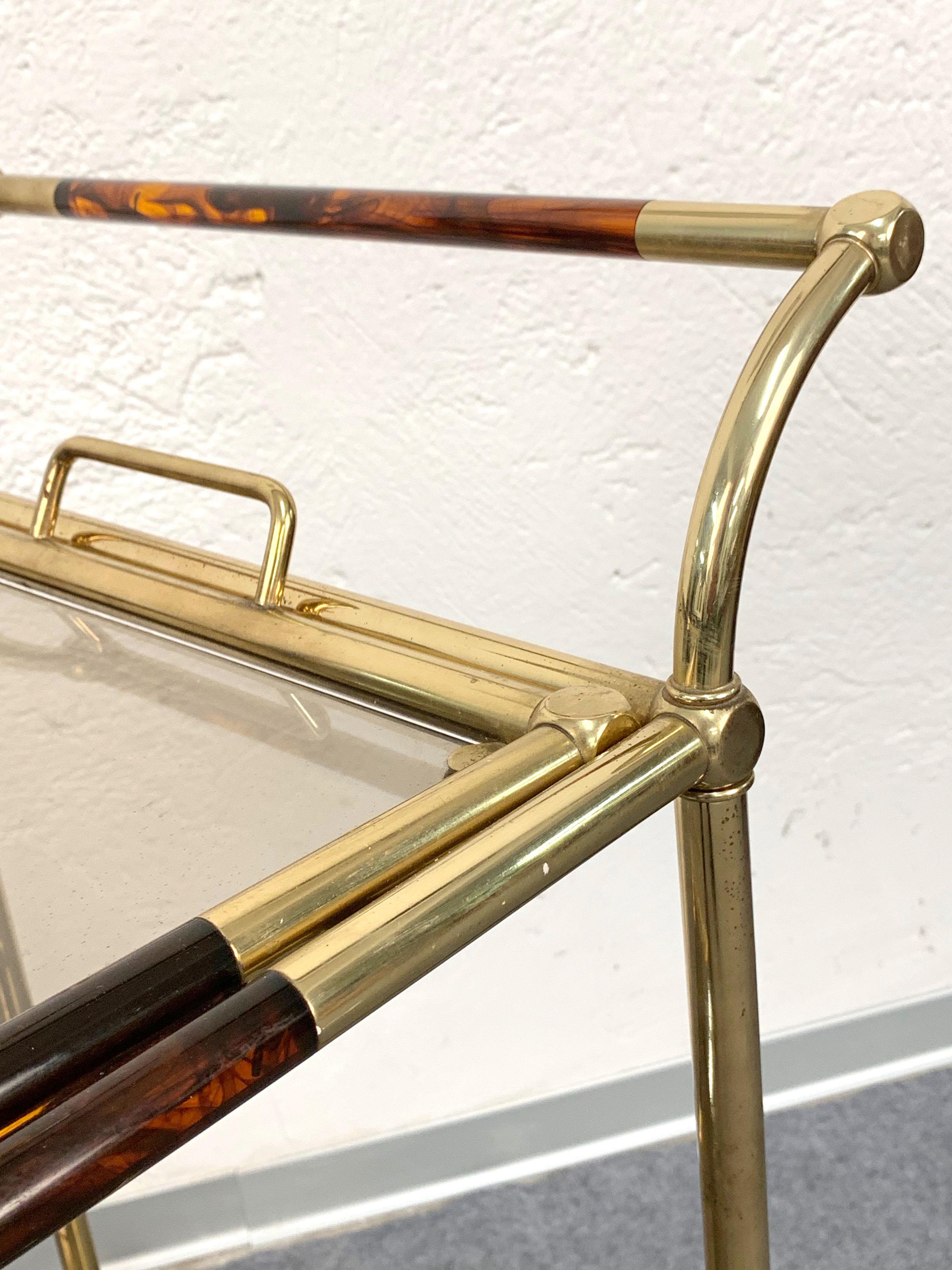 Elegant golden brass and tortoiseshell Lucite trolley. This item is attributed to Willy Rizzo and was produced in Italy during 1980s. 

This item is unique as it has the top becoming a wonderful service tray when needed. The bottom shelf has a