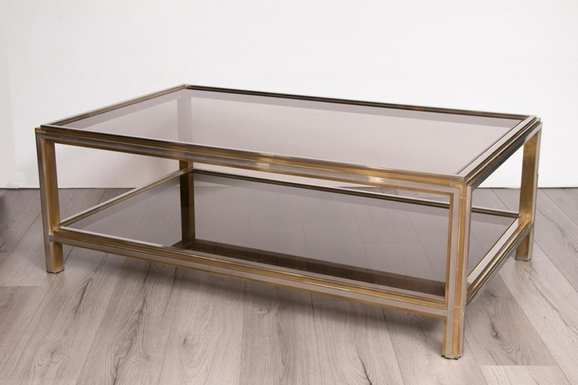 A Hollywood Regency coffee table designed by Willy Rizzo with brass and chrome frame and smoked glass top and shelf.