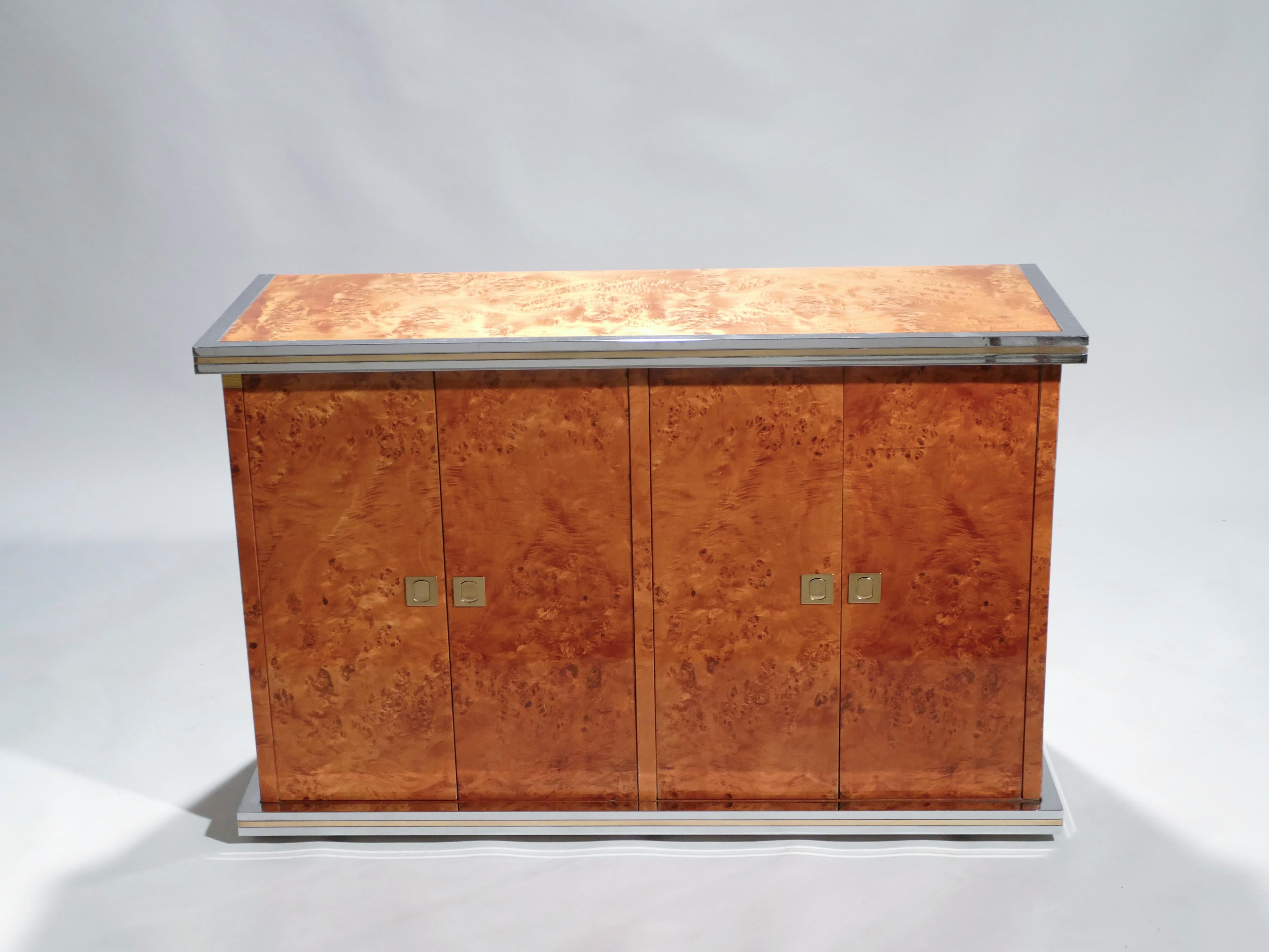 Rich burl wood is the eye-catching chief material in this beautiful, small credenza by Willy Rizzo. The wood sides and top swirl and ripple into shades of caramel and coffee brown, for a warm, glossy look. Brass and chrome accents, along the clean