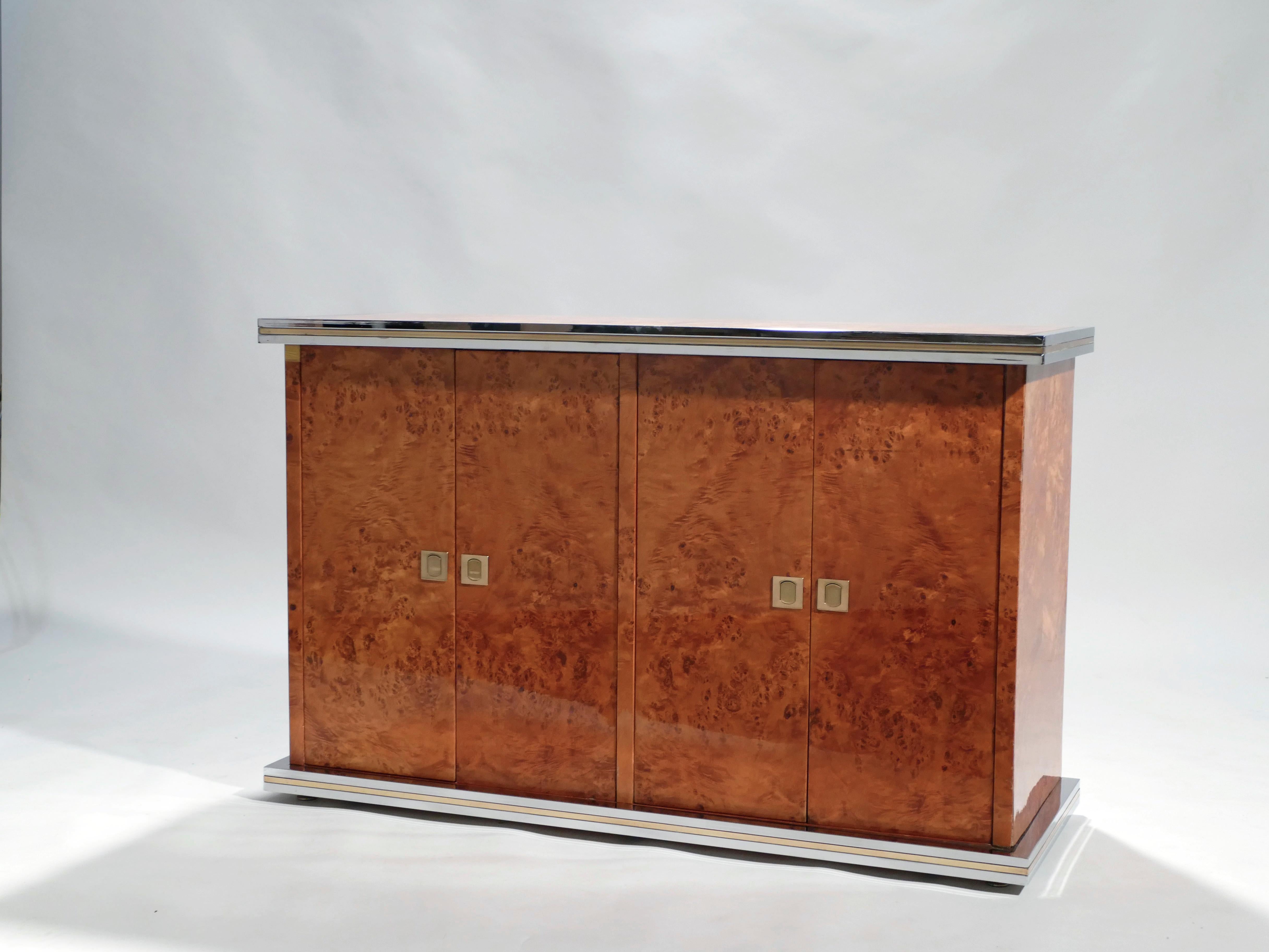 Rich burl wood is the eye-catching chief material in this beautiful, small credenza by Willy Rizzo. The wood sides and top swirl and ripple into shades of caramel and coffee brown, for a warm, glossy look. Brass and chrome accents, along the clean