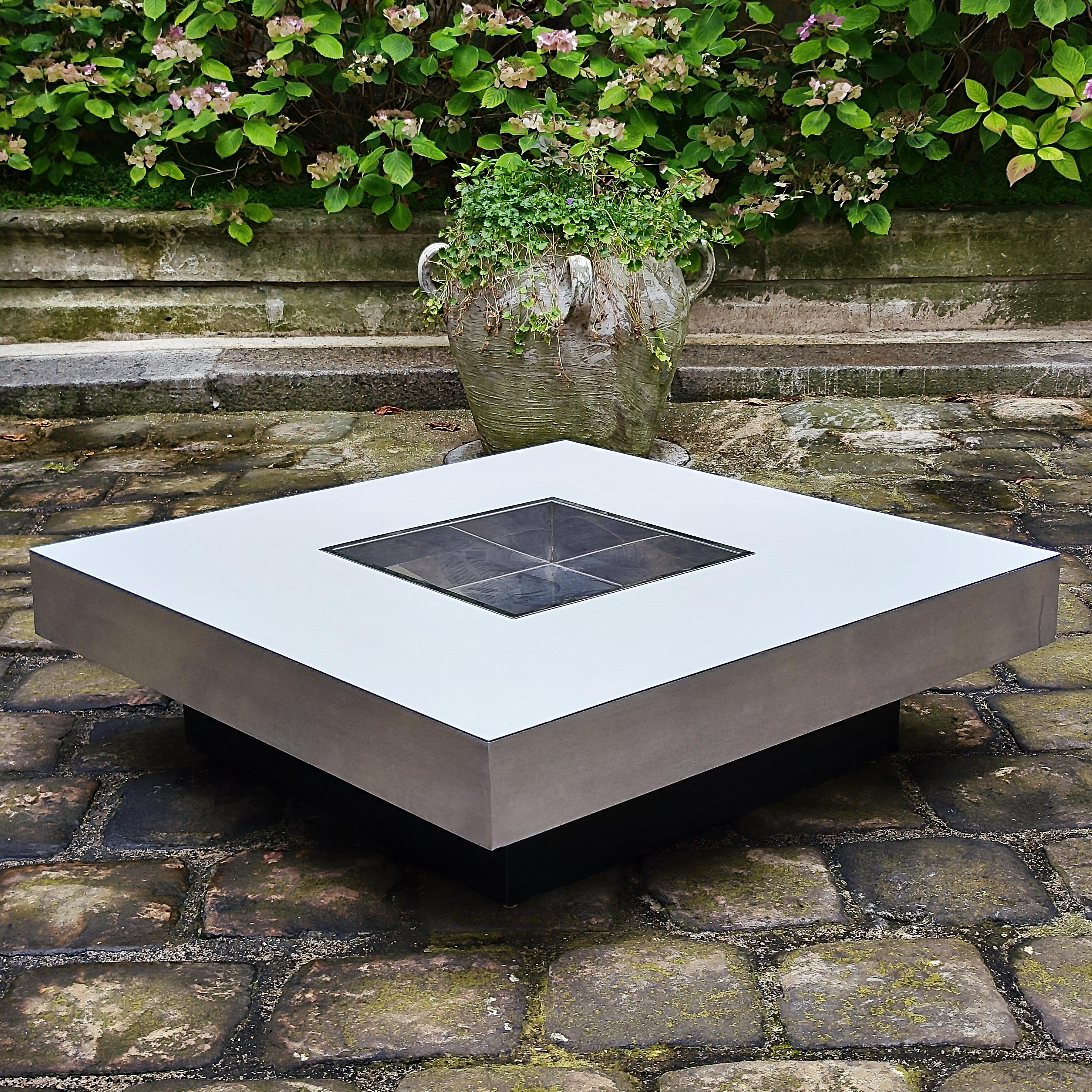 Willy Rizzo (1928-2013).
.
Table basse carrée en mélamine blanche et contours en métal brossé avec son bac à plantes servant de bar (inox) en partie centrale.
.
Dimensions : 
Carré de 98/99 cm de côté et hauteur d'environ 29 cm
.
Le plateau en