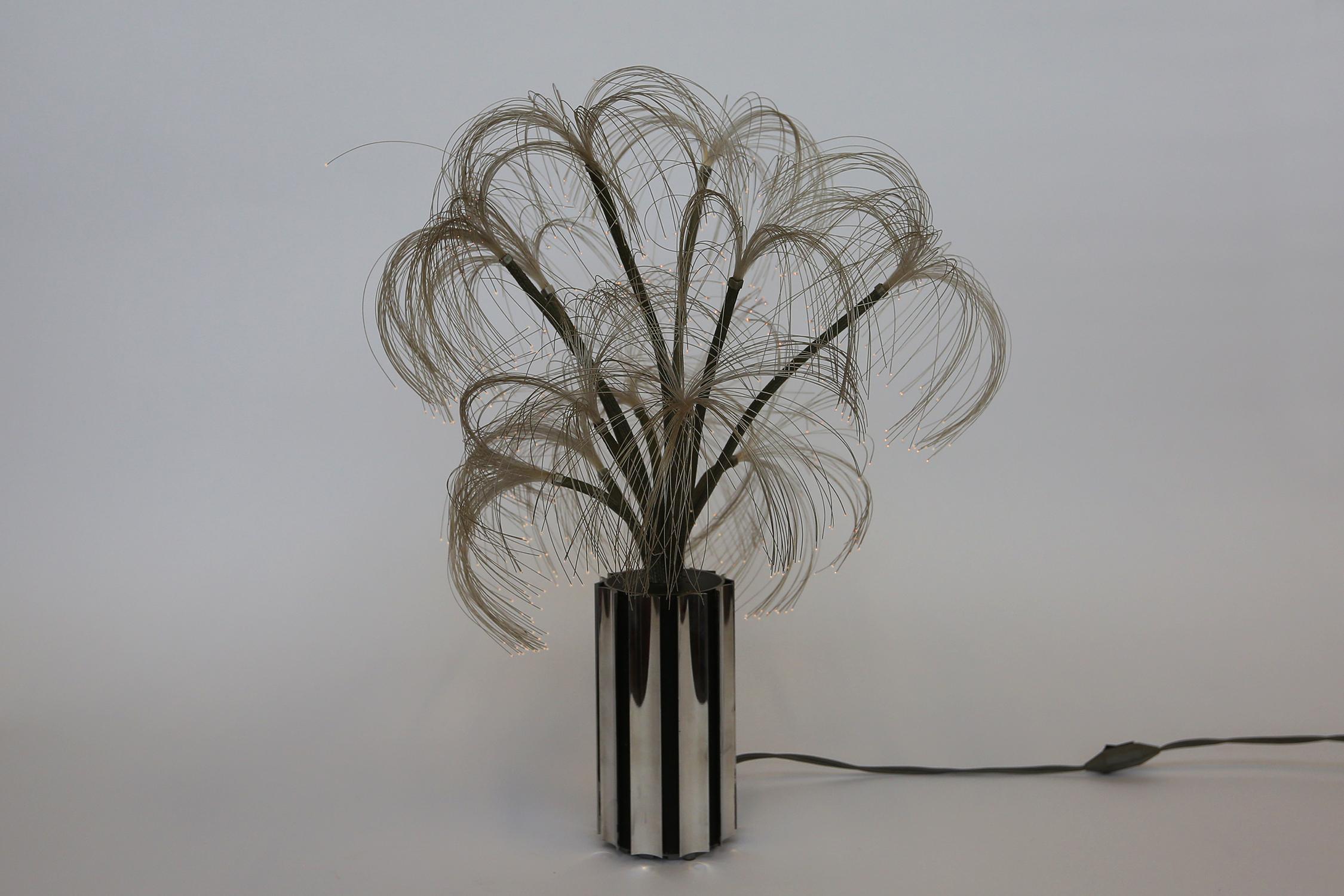 Atmospheric chrome table lamp, representing a palm tree. Chrome base with branches en at the end nylon wires. The end of the nylon wires lights up.