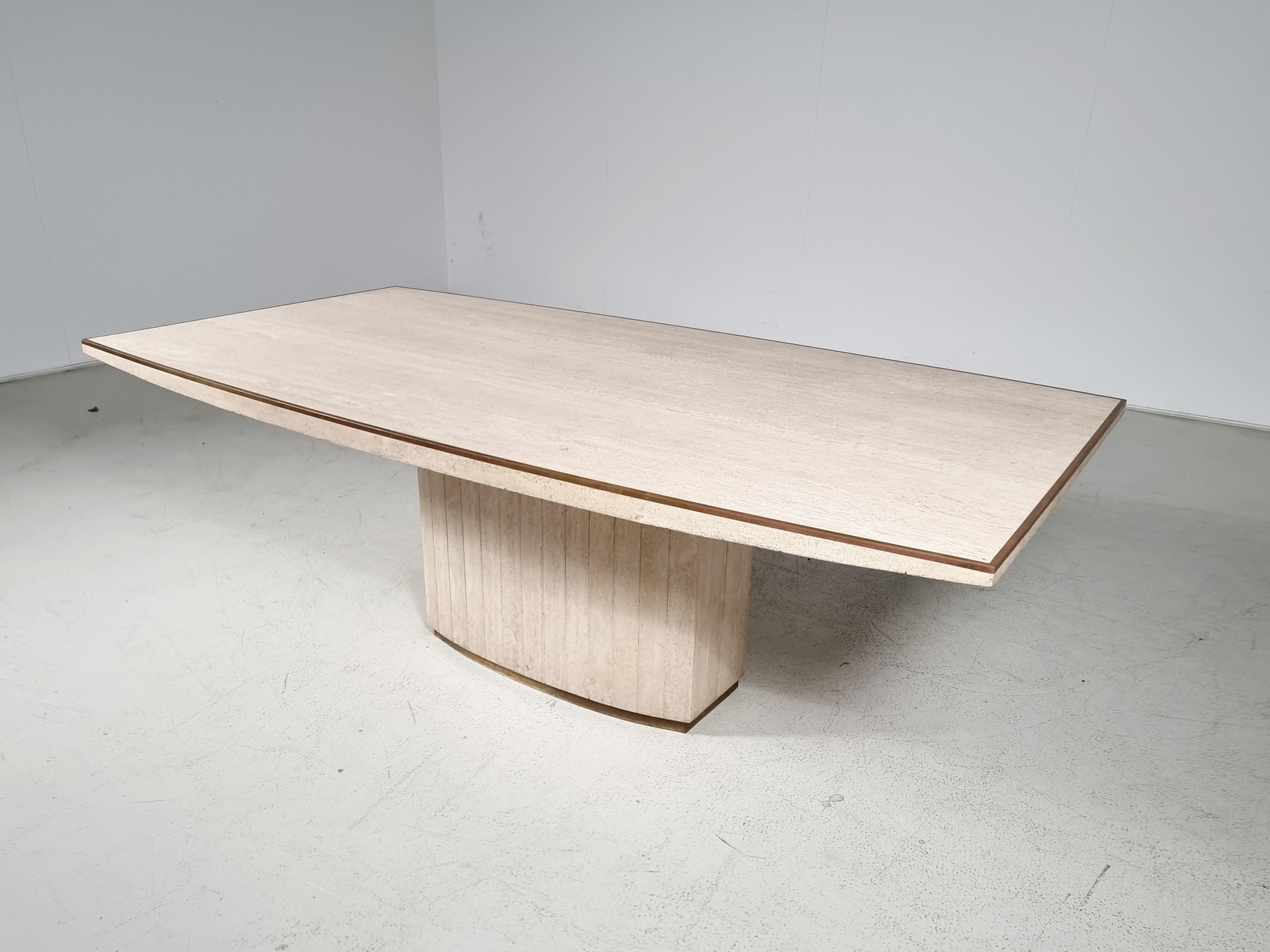 Willy Rizzo for Jean Charles dining table in travertine with brass details from the 1970s.

The base is also made of travertine slabs, which shape has a fine bend. At the bottom, the base is also finished with a brass strip. 

Very chic with the