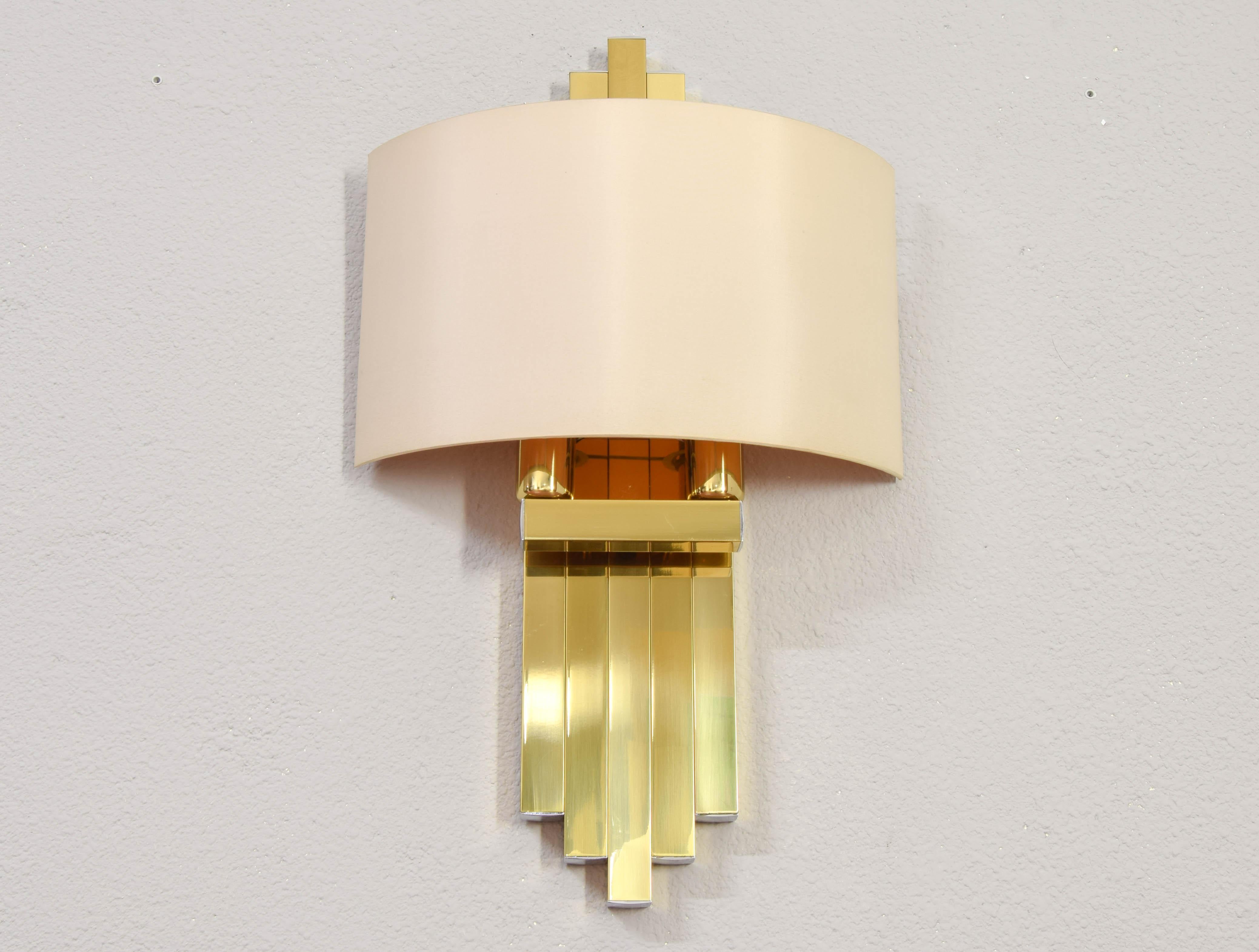 Sculptural wall light produced by Lumica BD in the 1970s in Spain.
A wonderful piece designed to dress a wall with elegance.
Body composed of golden steel bars and finished in brass with chrome finishes at the ends and beige satin