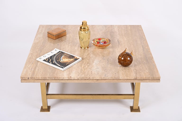 Midcentury square coffee table in travertine marble with brass base. This exceptional object was designed in Italy in the 1970s in the style of Willy Rizzo.

This stunning table features brass base and an outstanding quality Travertine marble top.