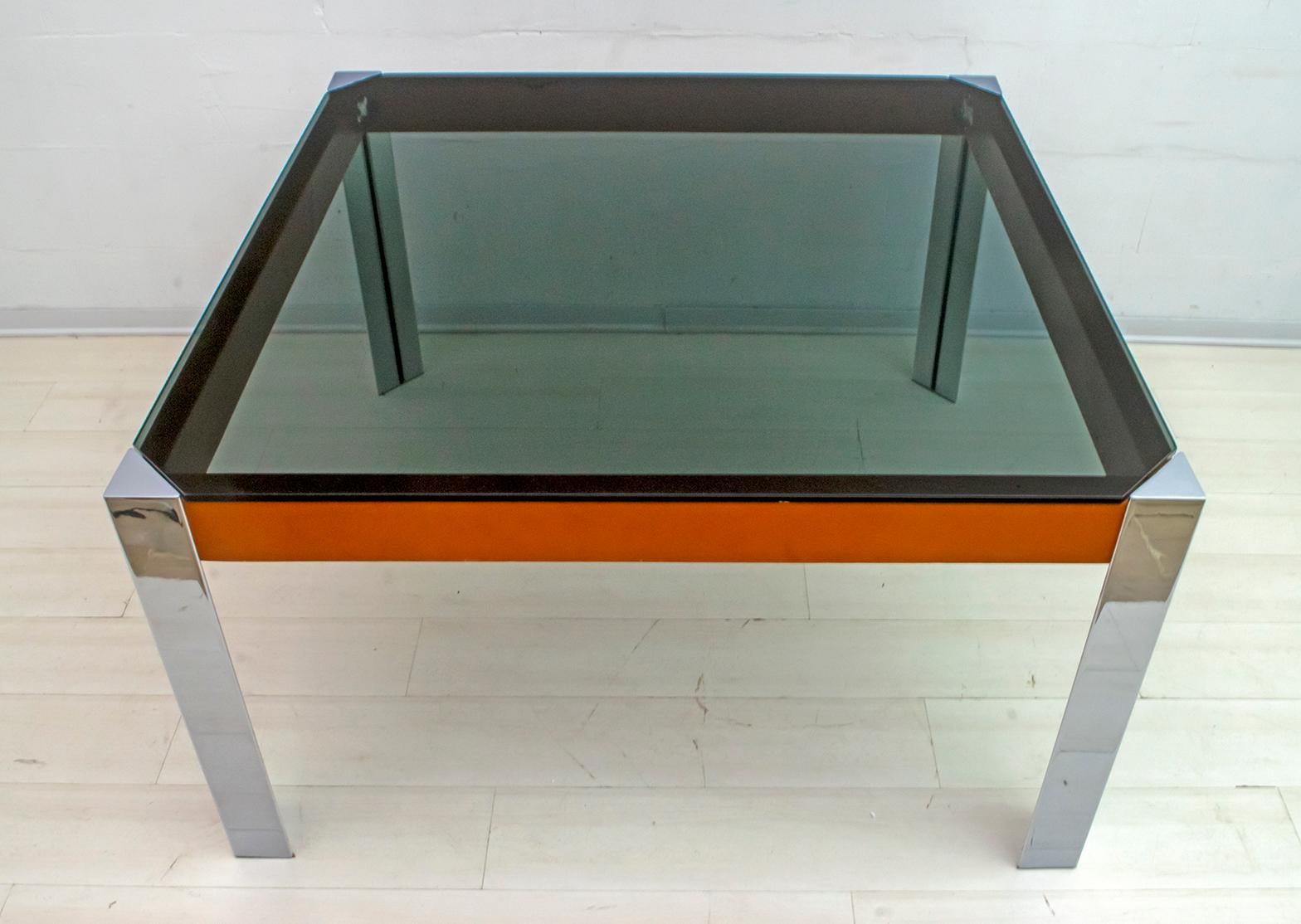 Beautiful dining or writing table in the style of Willy Rizzo, 1970s. The structure is in polished steel, the side bands are covered in genuine leather, the top in smoked glass. Very simple and elegant design. In good vintage condition.