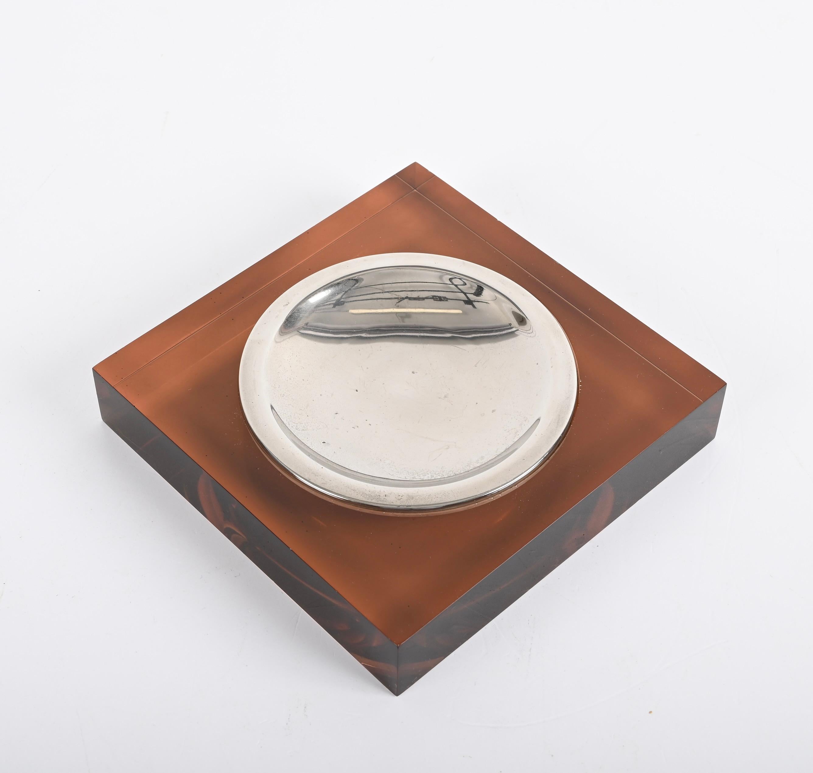 Wonderful dark amber lucite and chromed metal ashtray. This fantastic item was designed in Italy during the 1970s following the style of Willy Rizzo.

This ashtray is fantastic because it has a wonderful straight-lined dark amber lucite on the